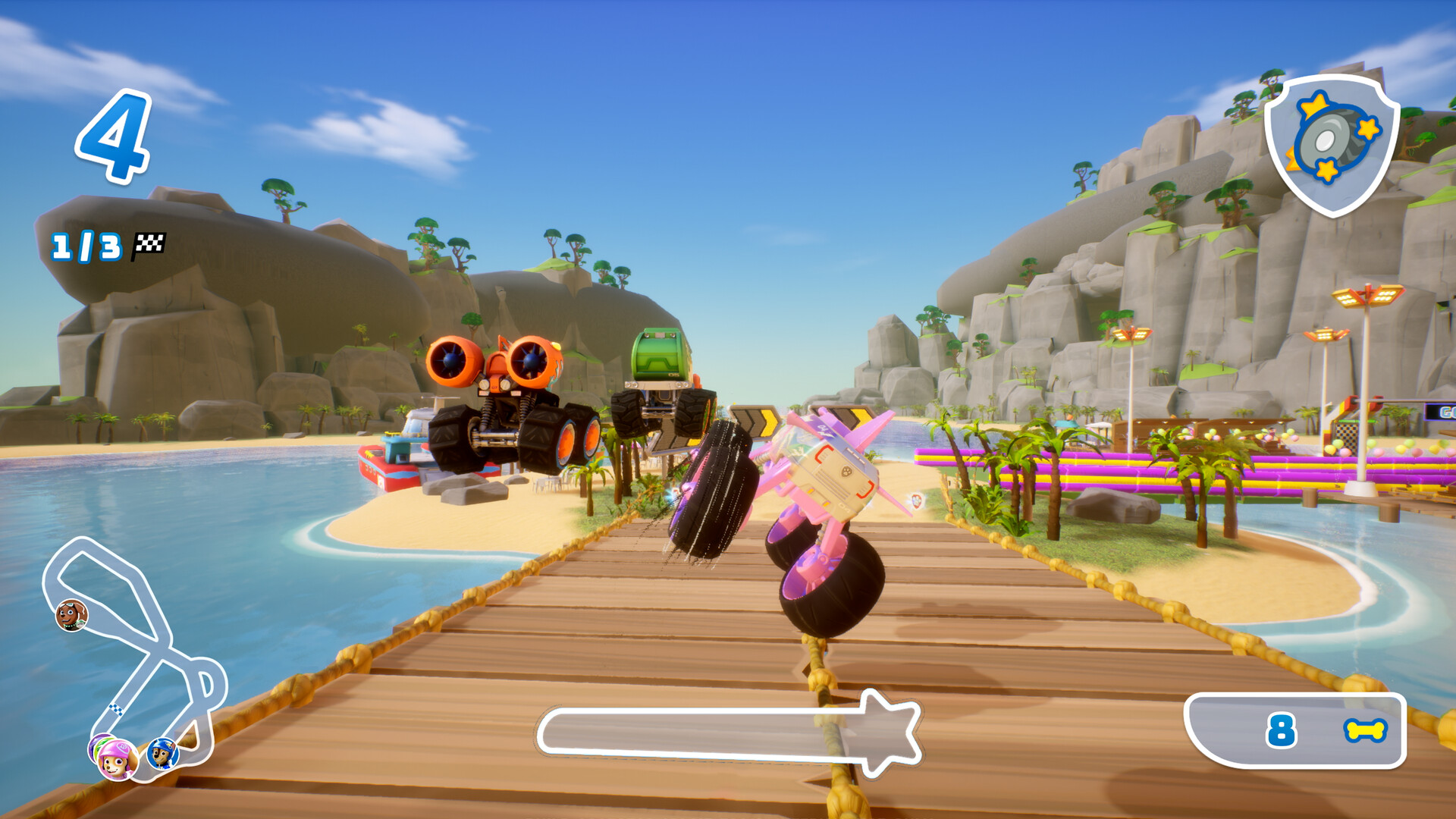 Eine Cartoon-Rennszene mit Monstertrucks auf einer Holzbrücke, einem Strand und blauem Himmel.