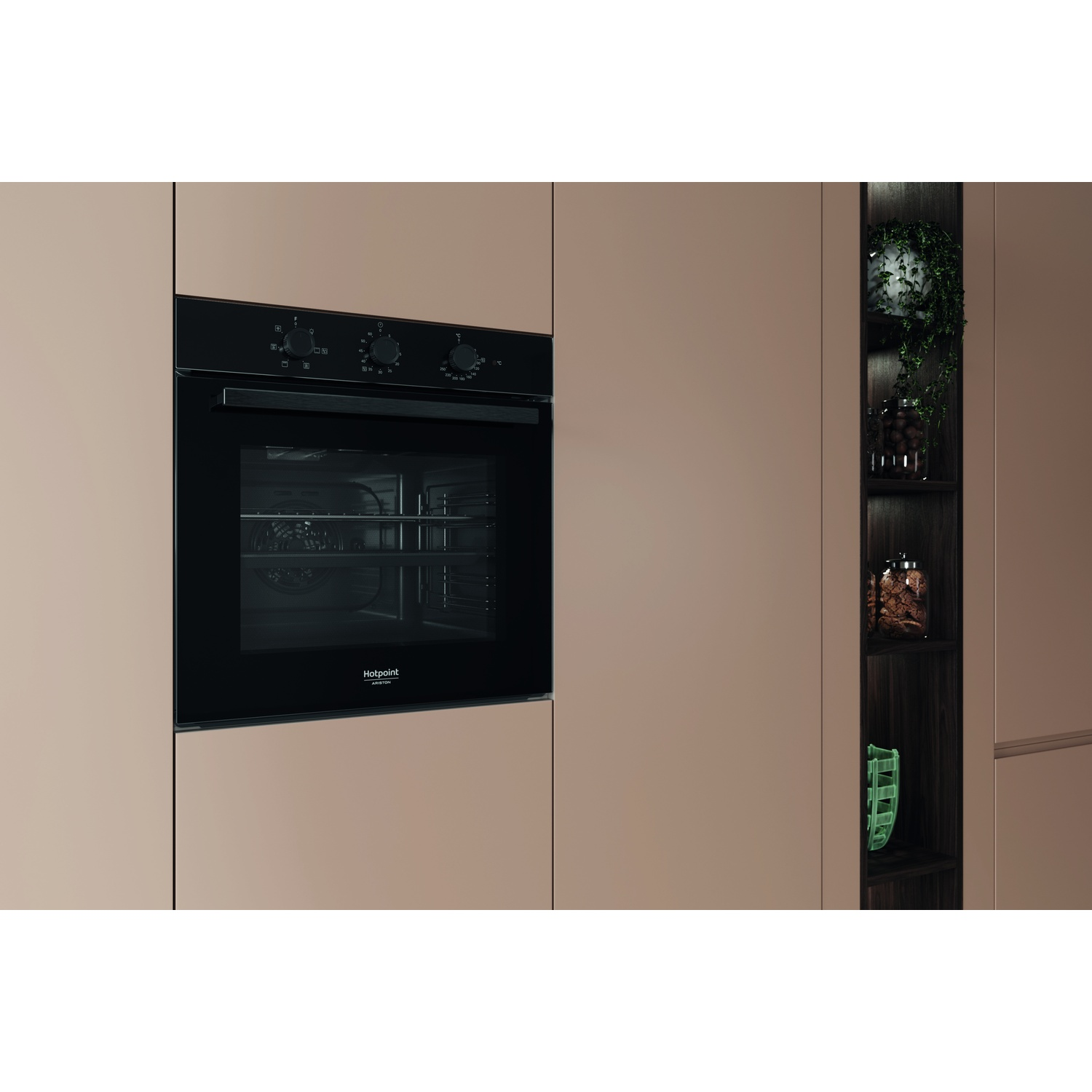 Un forno nero Hotpoint è integrato in un mobile da cucina. Un ripiano in legno scuro ha piante e barattoli. L'armadio è marrone chiaro.