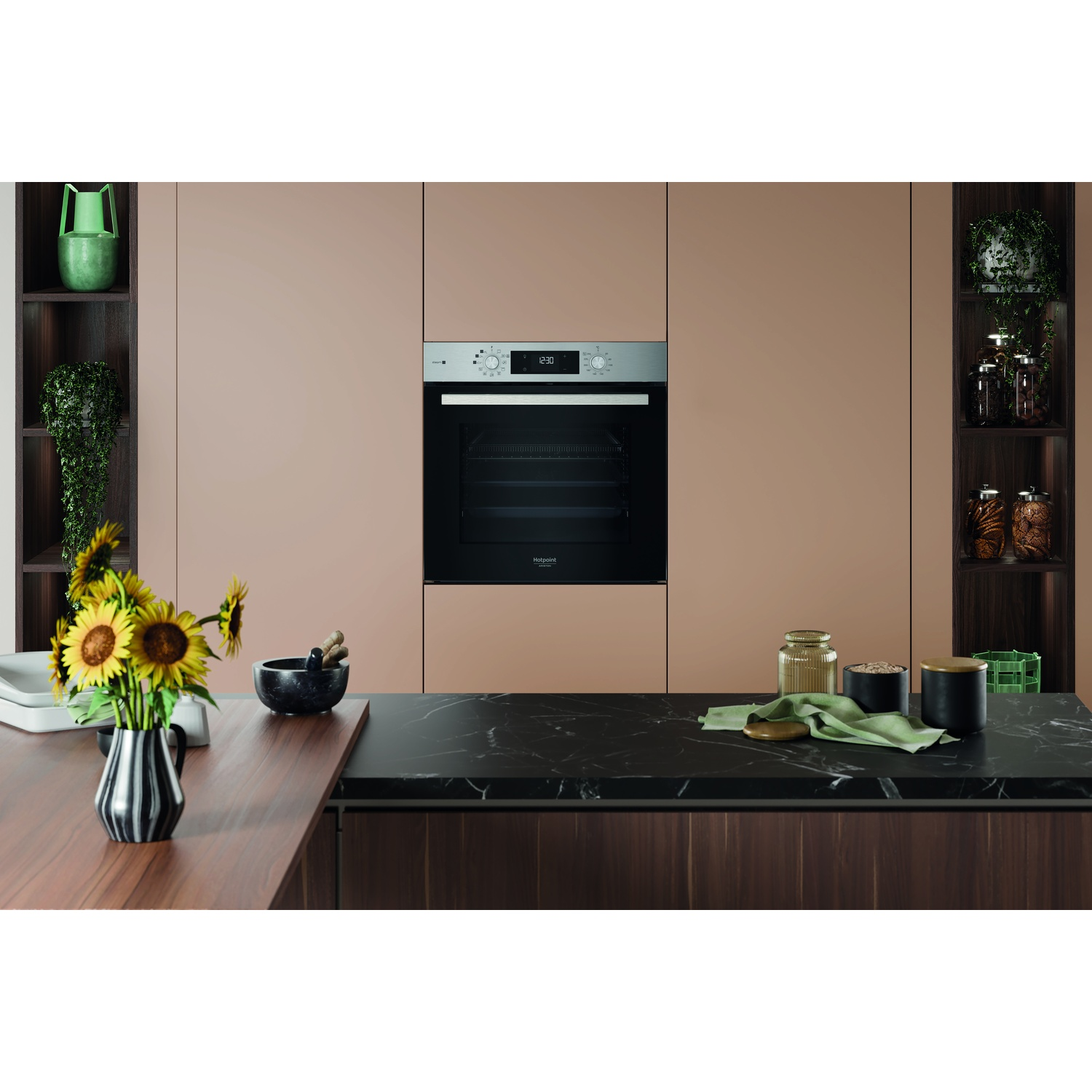 Scena cucina: Forno, girasoli e piano di lavoro con oggetti decorativi. Mensole con piante su entrambi i lati.
