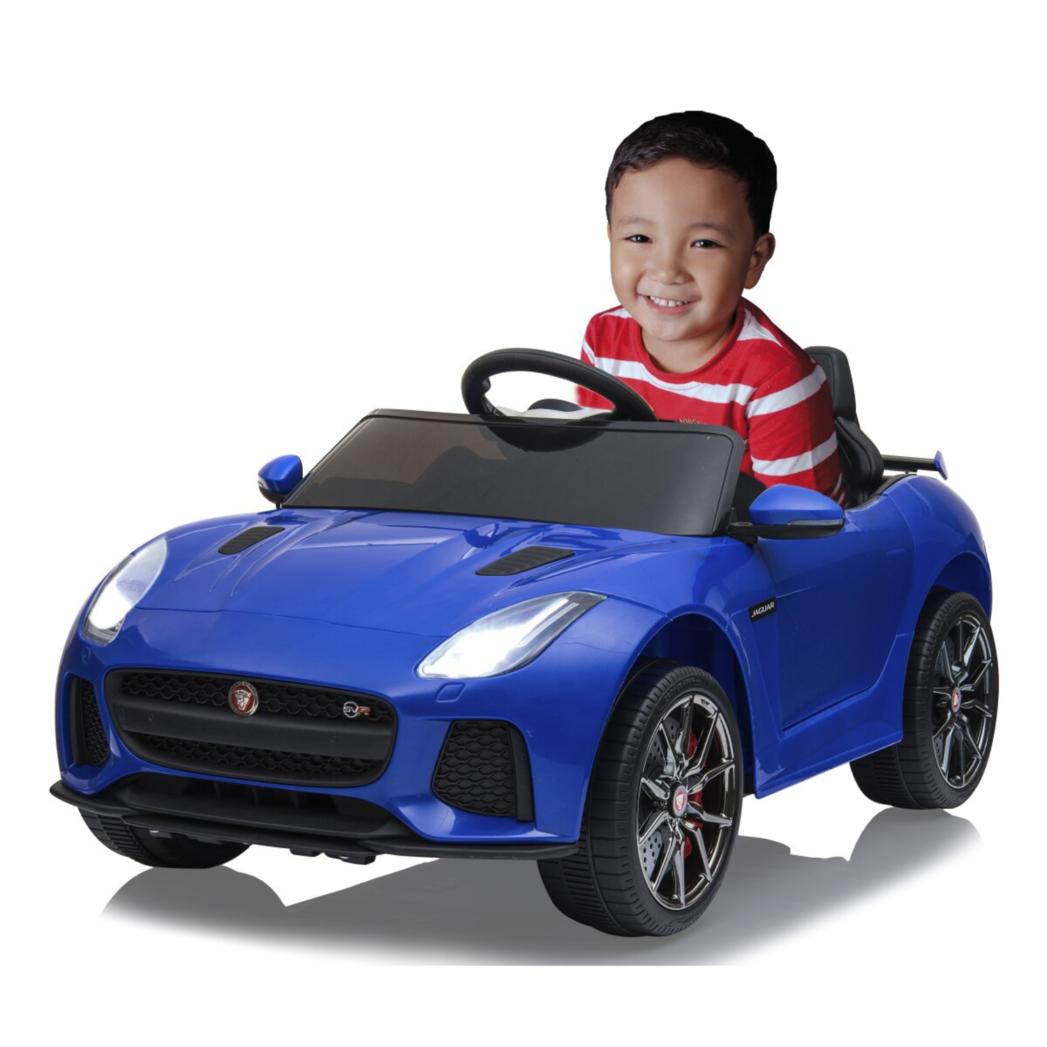 Een jongen glimlacht terwijl hij in een blauwe Jaguar-speelgoedauto zit. Hij draagt een rood-wit gestreept shirt.