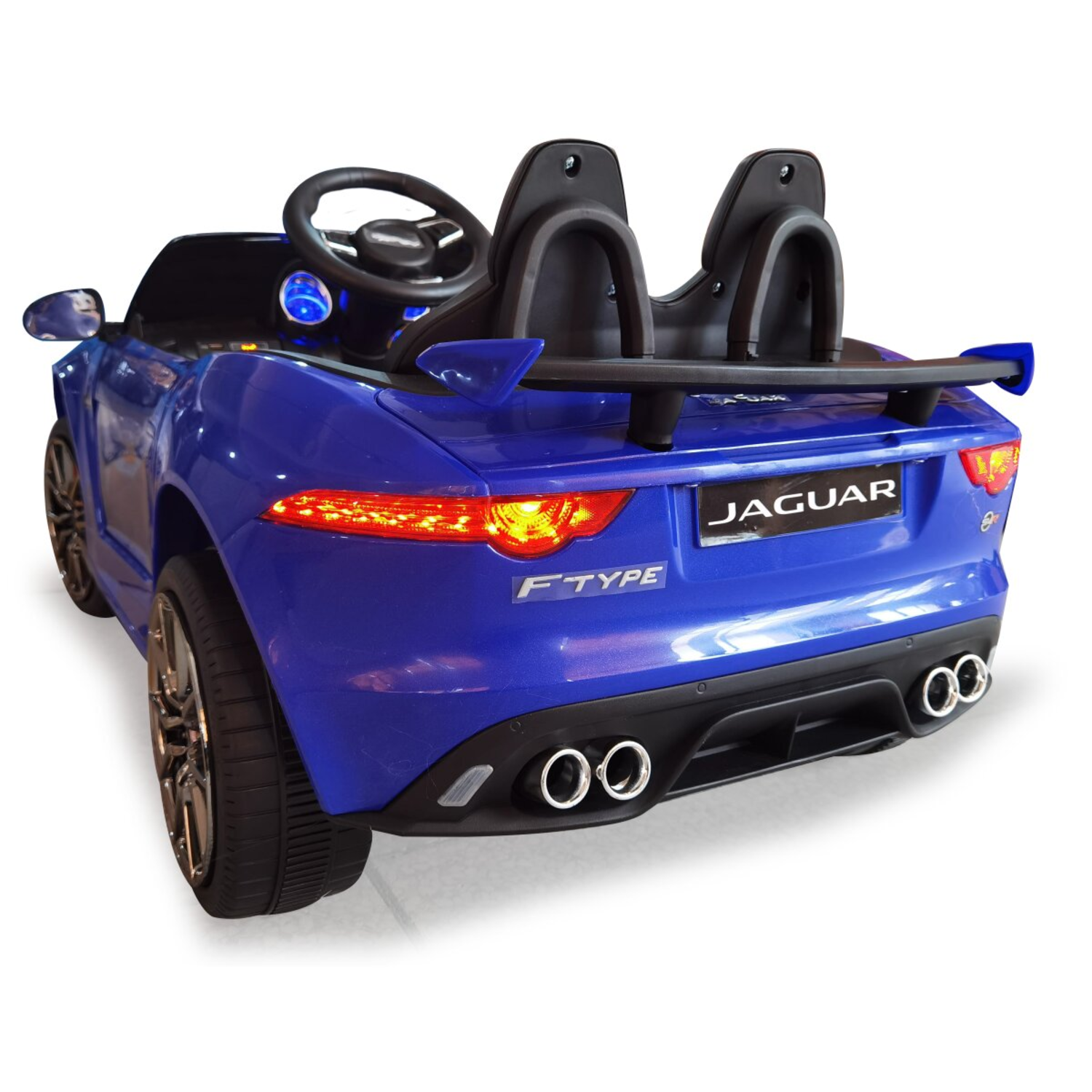 Een blauwe speelgoed Jaguar F-Type auto. Het heeft een zwart interieur, een stuur en twee zwarte stoelen. De achtergrond is wit.