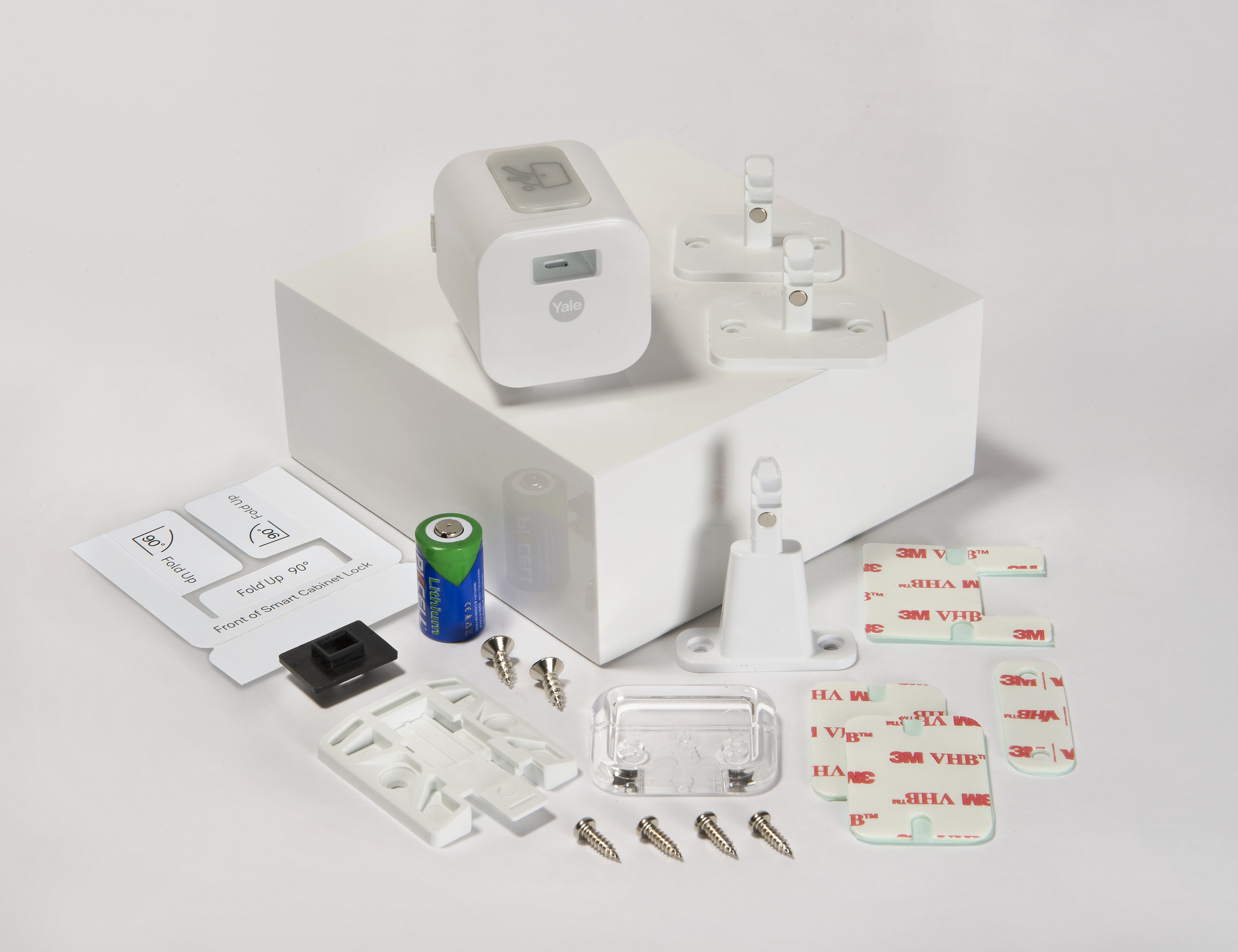 Ein weißes Yale Smart-Schrankverriegelungs-Kit mit Komponenten: Schloss, Montagehalterungen, Schrauben, Batterie und Klebepads.
