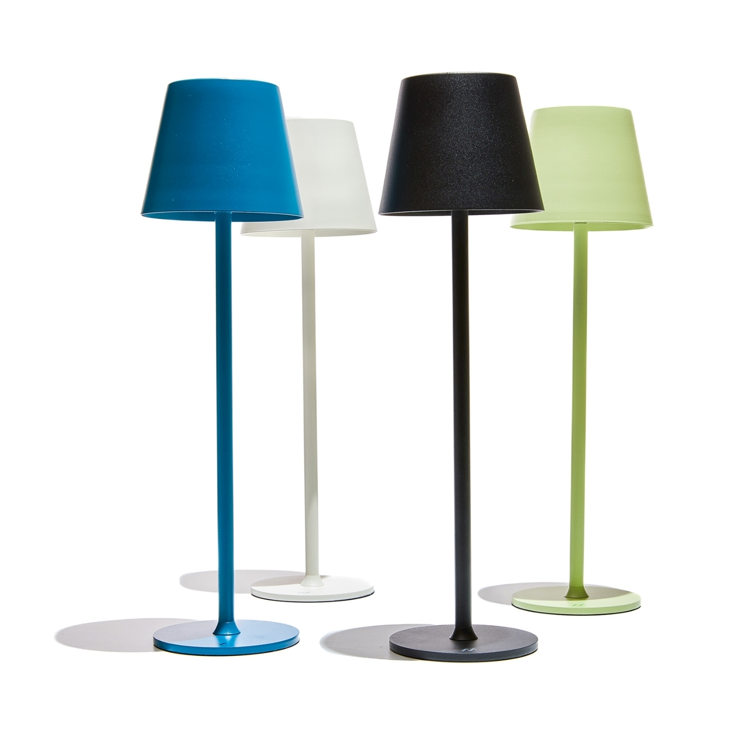 Quattro lampade moderne con paralumi colorati: blu, bianco, nero e verde. Sono su una superficie bianca. Ognuna ha una base abbinata.