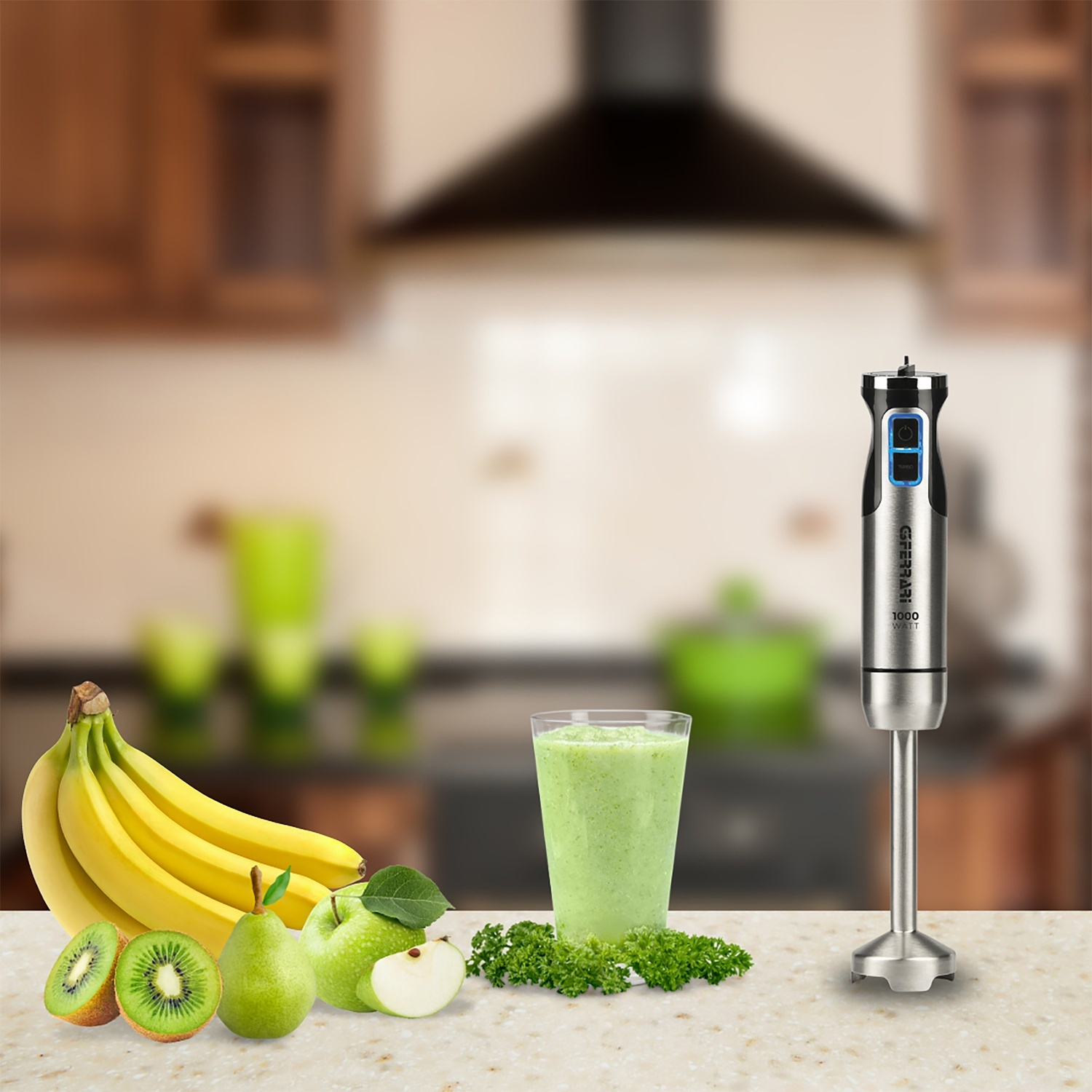 Un frullatore, un bicchiere di frullato verde, banane, kiwi, mela e pera su un piano di lavoro con sfondo sfocato della cucina.