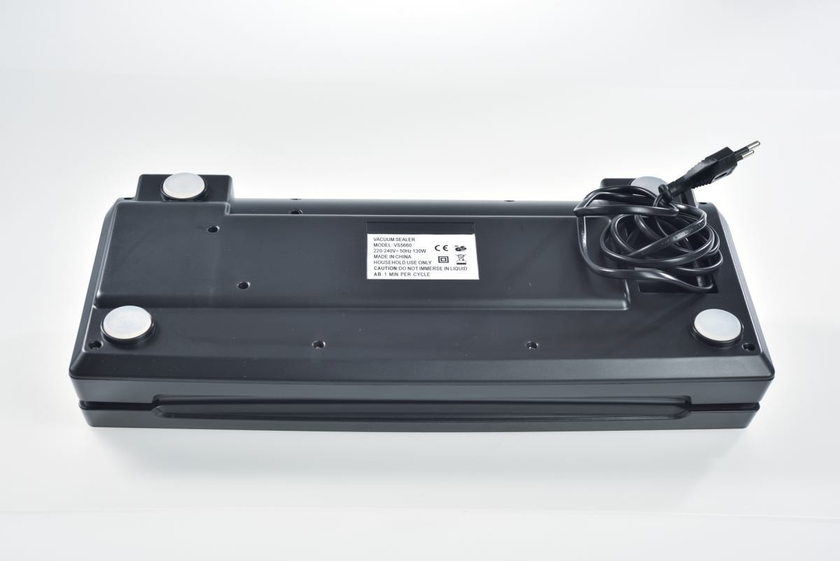 Czarna zgrzewarka próżniowa z przewodem zasilającym na białej powierzchni. Posiada etykietę i cztery okrągłe, srebrne magnesy.