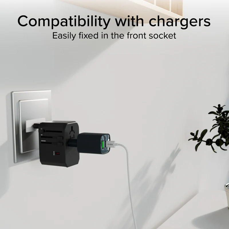 Czarny uniwersalny adapter jest podłączony do gniazdka ściennego, z podłączoną czarną ładowarką. Widoczny jest biały kabel i zielone światło.