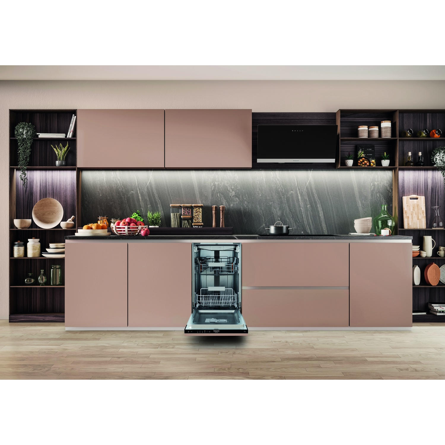 Cucina moderna con lavastoviglie aperta. Mobili rosa, piano scuro e pavimento in legno. Ripiani con decorazioni visibili.