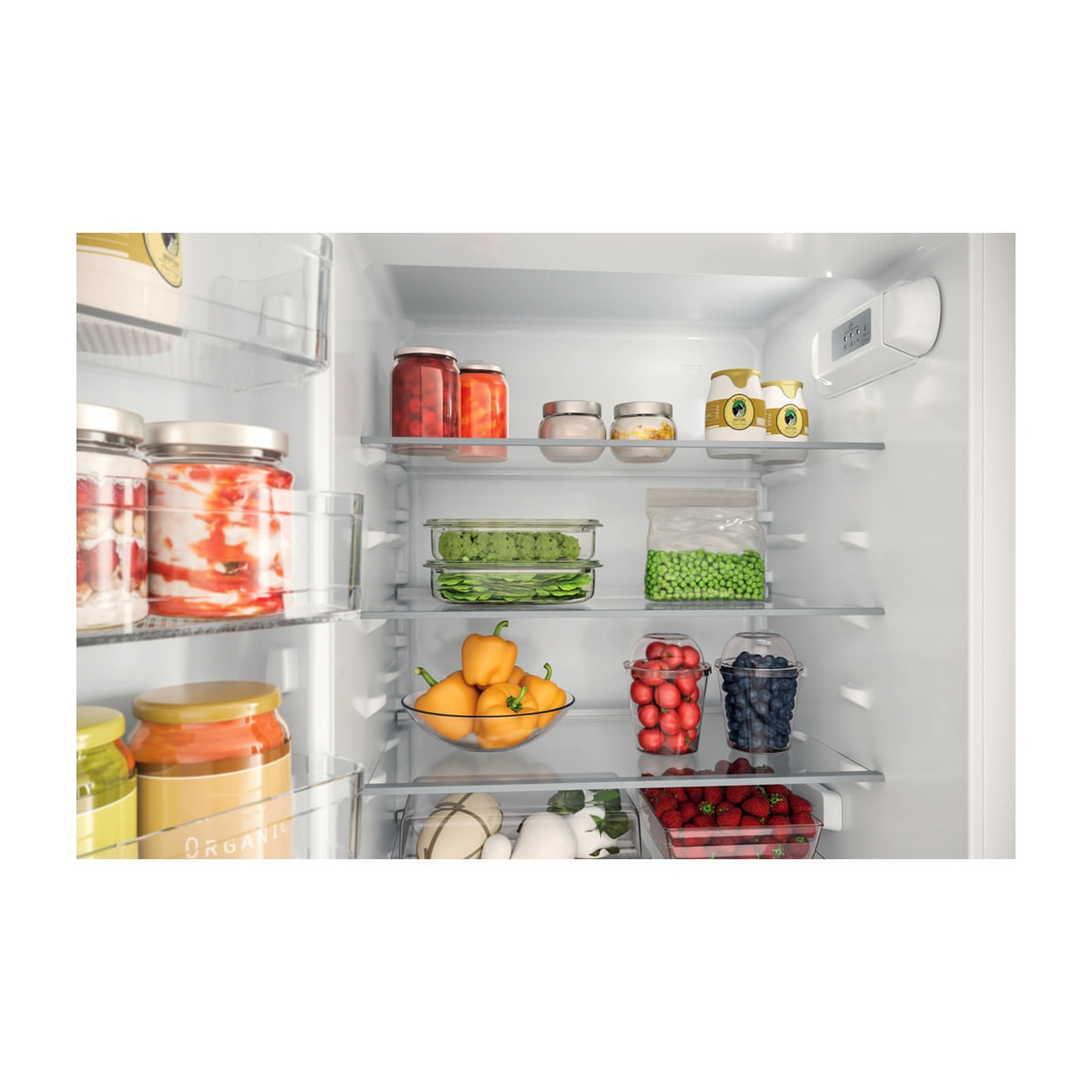 All'interno di un frigorifero pieno di vari alimenti. Vasetti di conserve, verdure e bacche sono ordinatamente disposti sugli scaffali.