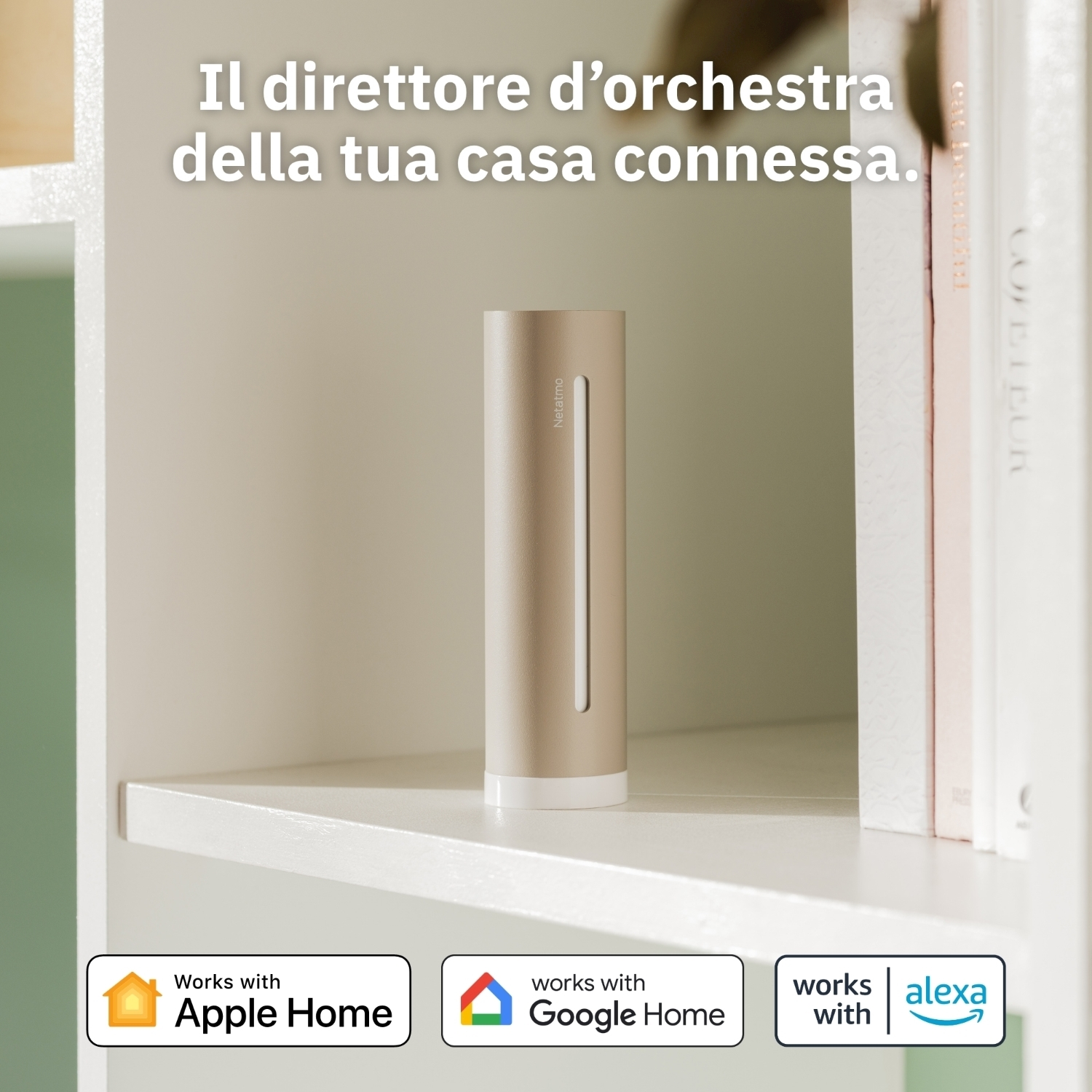 Un dispositivo Netatmo dorato su una mensola bianca. Accanto libri. Loghi Apple Home, Google Home e Alexa sotto.