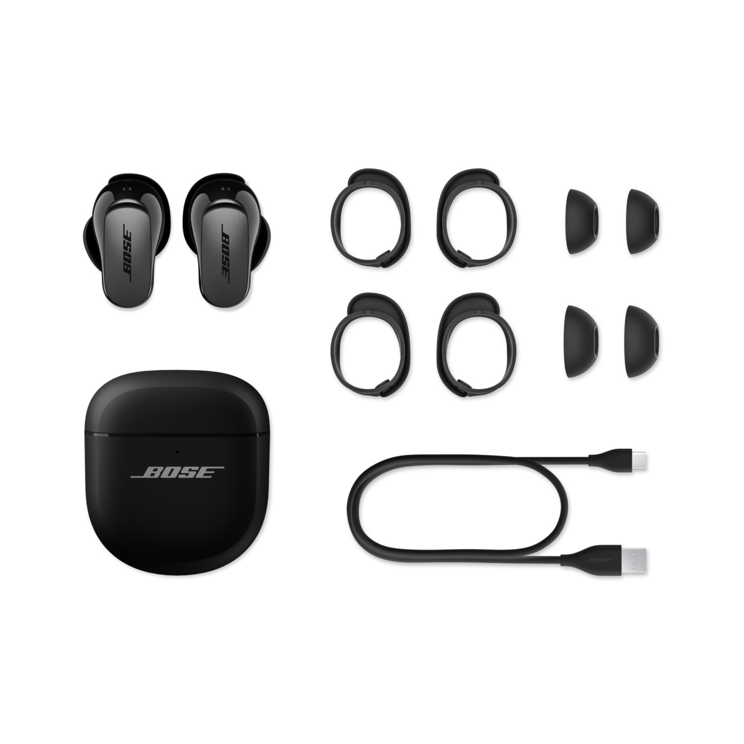 Black Bose earbuds, charging case, ear tips, and cable on white background. Accessories for wireless listening.