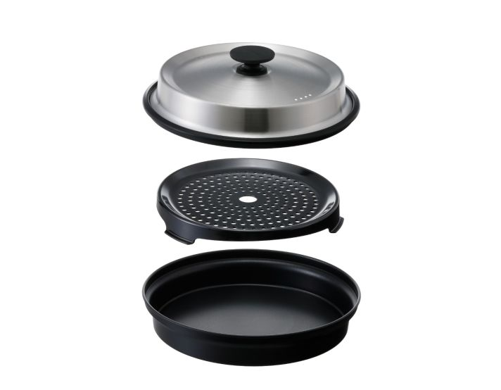 Rozłożony parowar. Składa się ze stalowej pokrywy, czarnej perforowanej tacy i czarnej podstawy, wszystkie izolowane na białym tle.