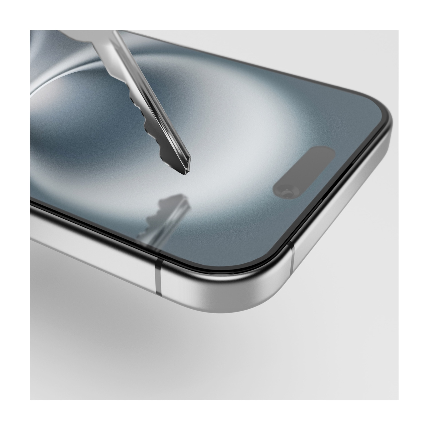 Chiave d'argento sopra uno smartphone. Il telefono è argentato, con schermo scuro. Sfondo bianco. La chiave è leggermente sfocata.
