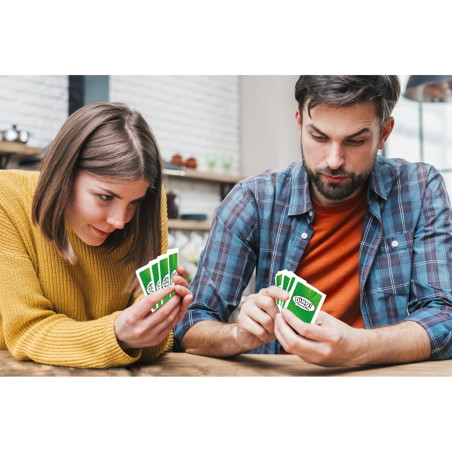 Due persone guardano delle carte. Una donna con un maglione giallo e un uomo con una camicia a quadri. Le carte sono verdi con testo bianco.