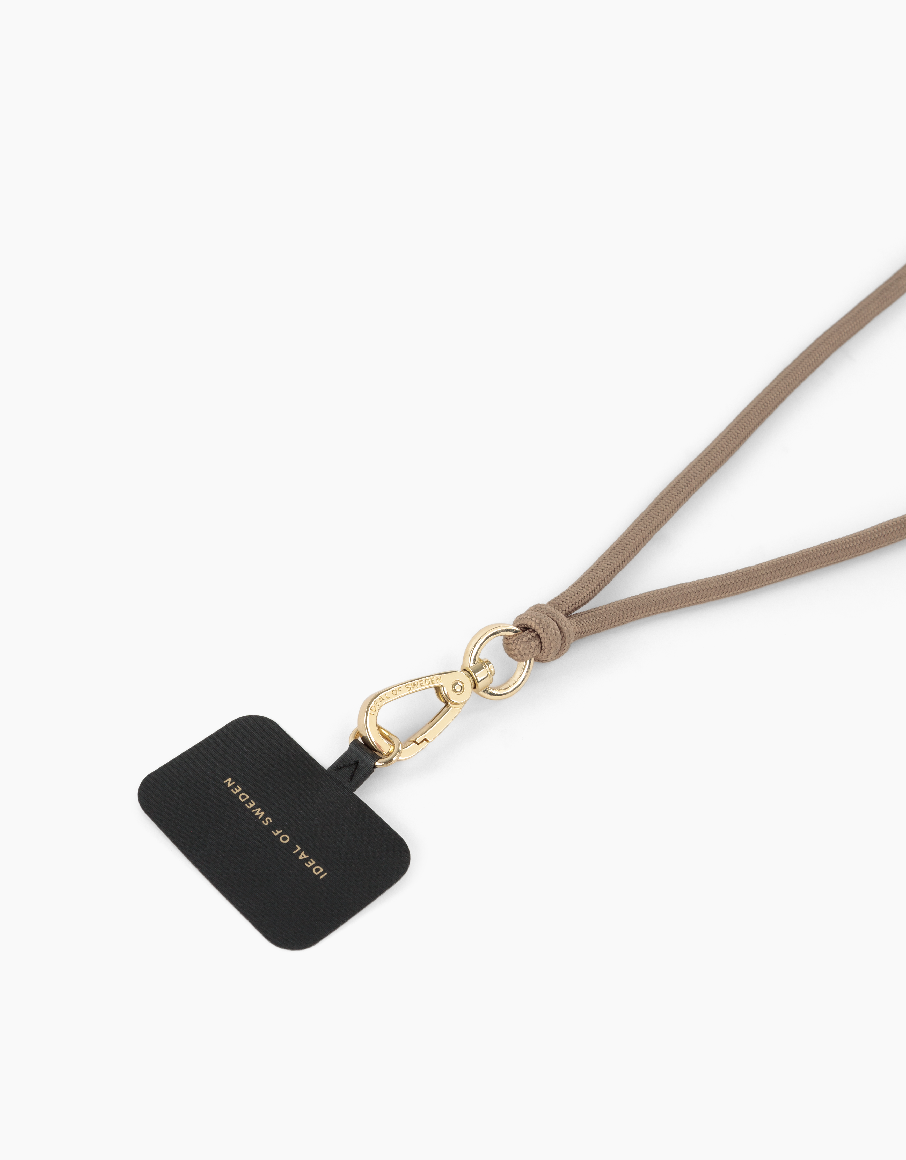 Ein schwarzes Telefonzubehör mit goldenem Verschluss und beigefarbenem Lanyard. Auf dem Zubehör steht 'Ideal of Sweden'.