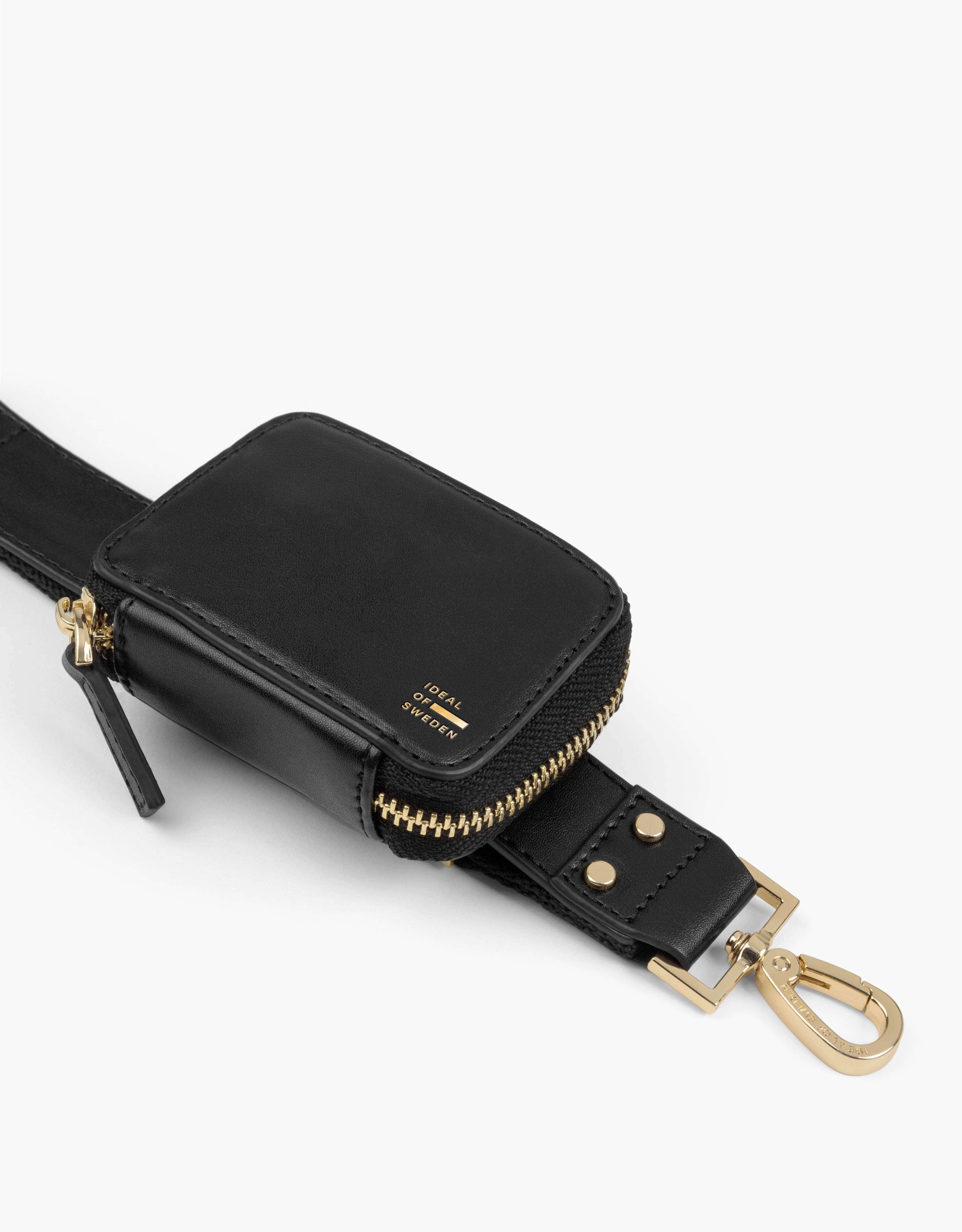 Schwarze Ledertasche mit goldenem Reißverschluss und Ideal of Sweden-Text, an Gurt und Verschluss, auf weißem Grund.