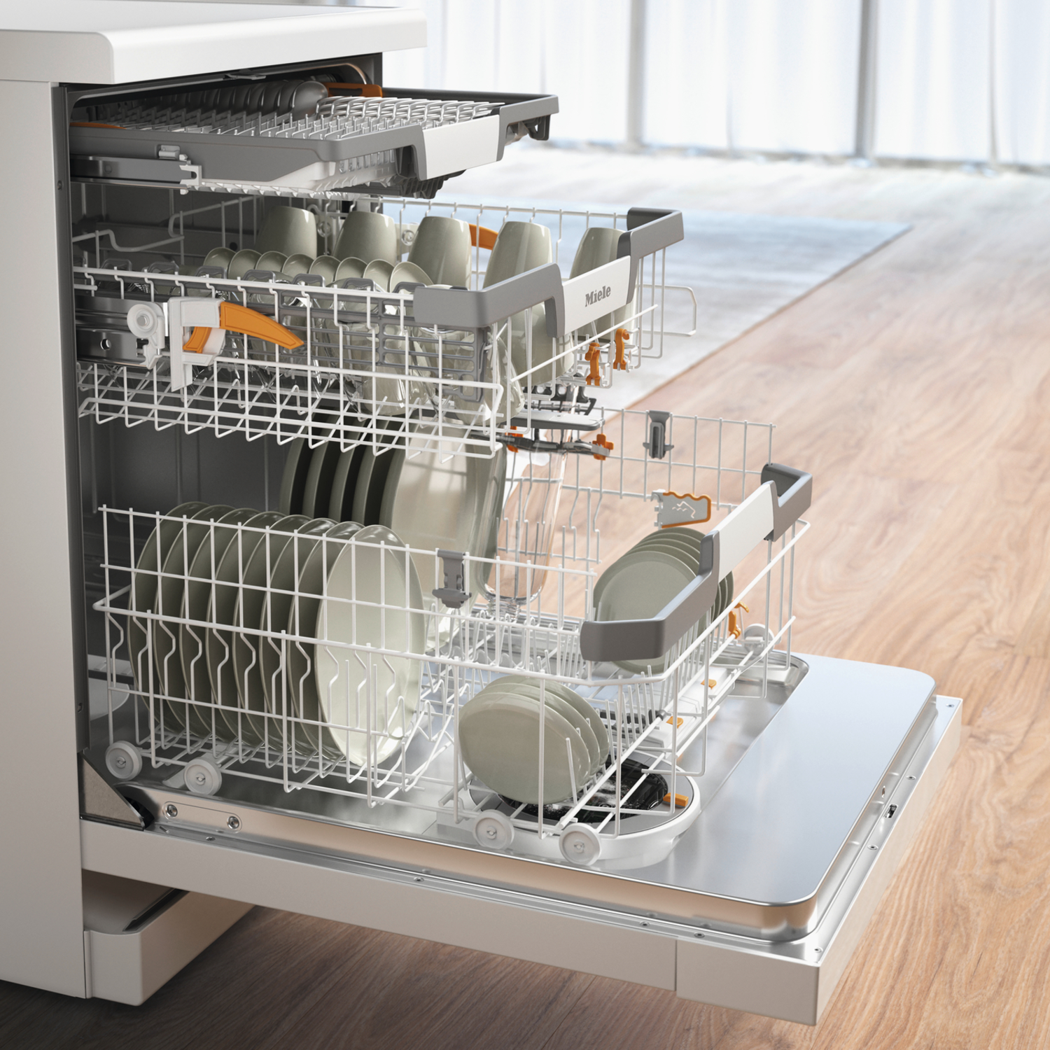 An open dishwasher loaded with dishes, glasses, and cups. The machine is white with orange accents, set on a wooden floor.