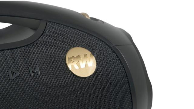 Nahaufnahme eines schwarzen Lautsprechers mit goldenem RW-Logo. Der Lautsprecher hat eine strukturierte Oberfläche und einen Griff.