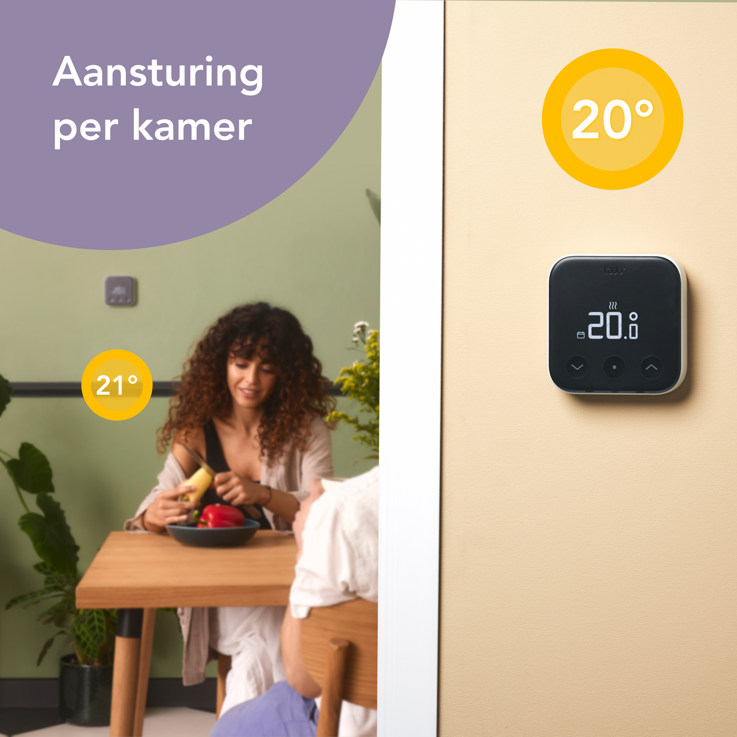 Een vrouw bereidt eten aan een houten tafel. De kamer heeft een thermostaat aan de muur. De achtergrond is een groene muur.