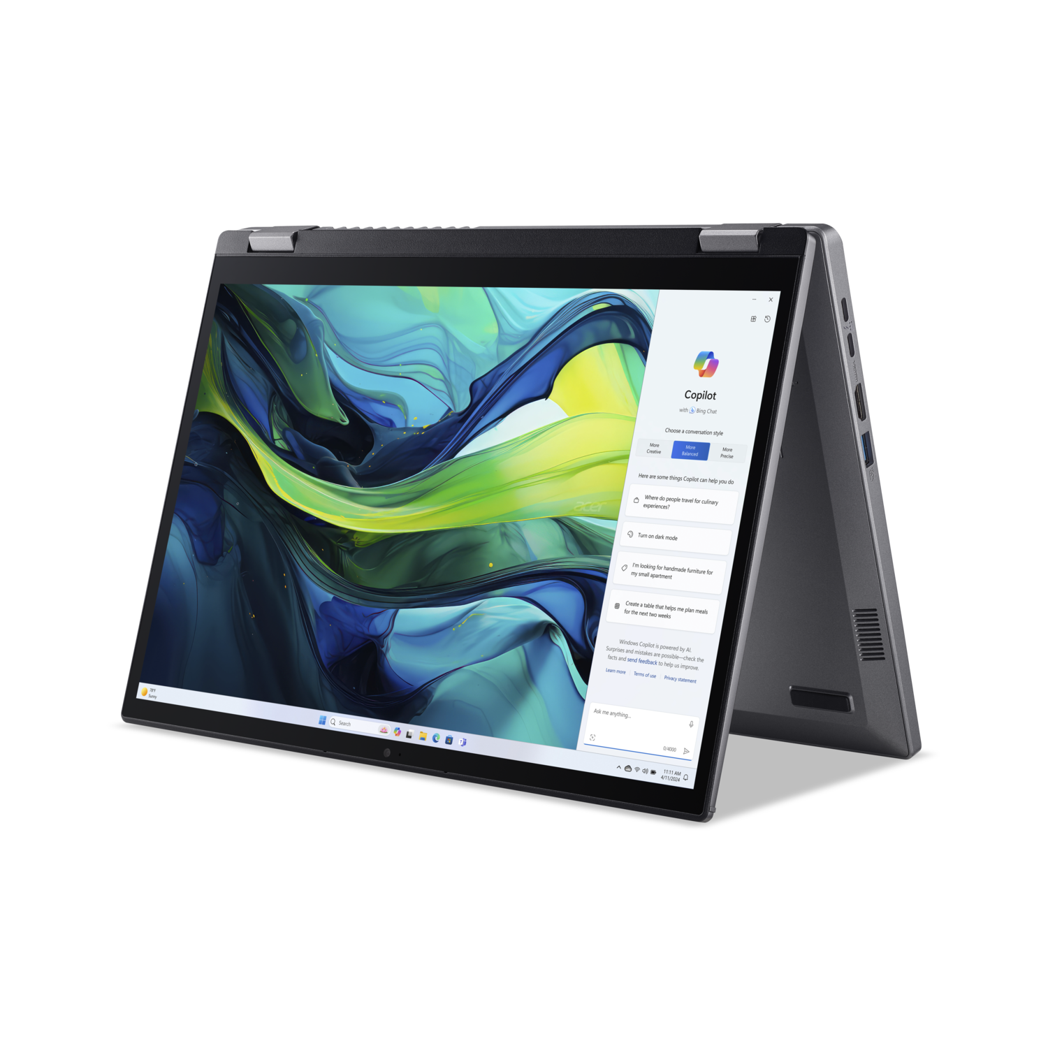 A gray laptop is open, showing Copilot on the screen. The screen displays abstract art. The laptop is on a black surface.
