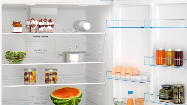 İçinde yiyecekler olan açık bir buzdolabı: kavanozlar, salata, karpuz, yumurta, bardakta kiraz ve bir tencere. Raflar görünür.