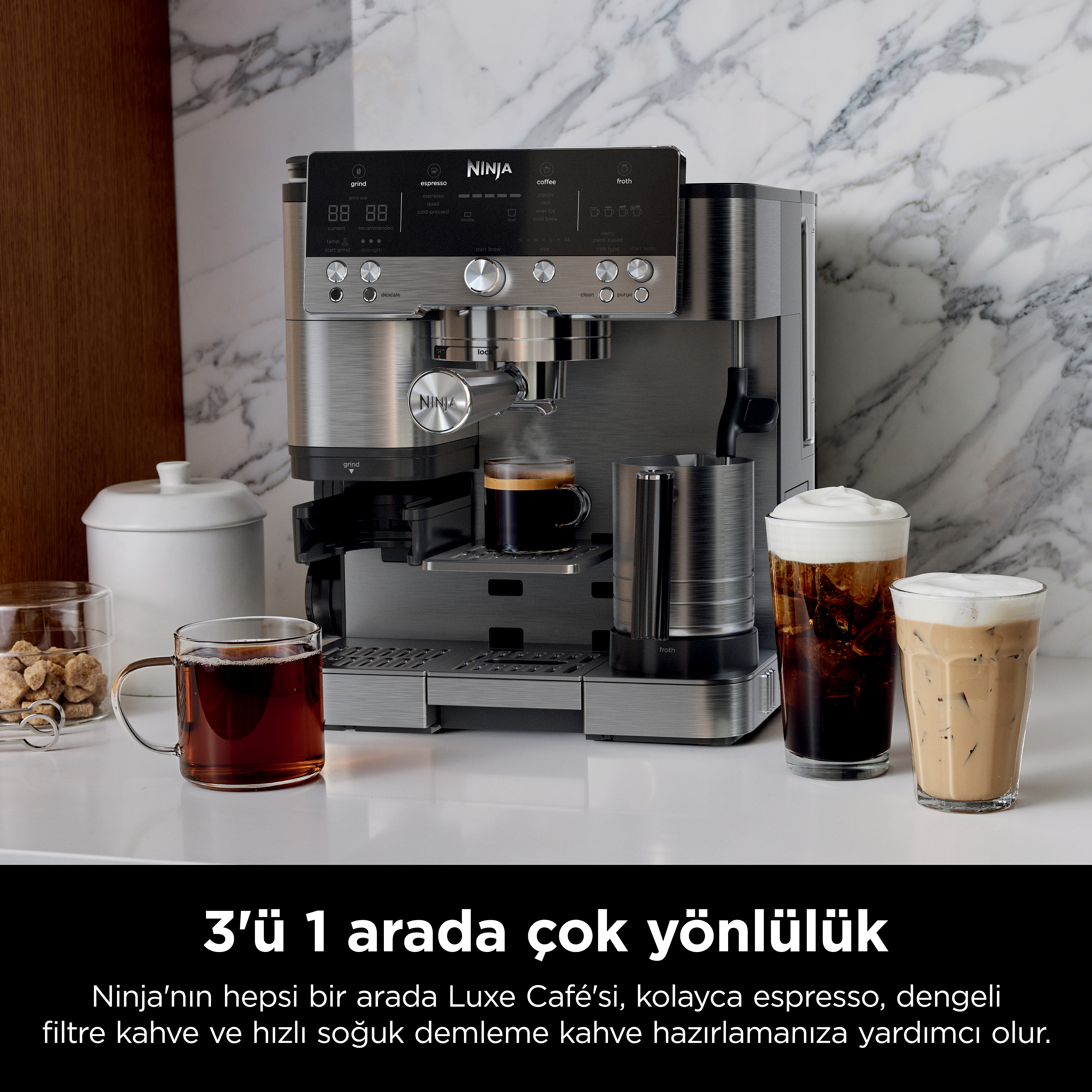 Beyaz yüzeyde bir fincan espresso, iki buzlu kahve ve şeffaf bir fincan çay ile gümüş renkli bir Ninja kahve makinesi.