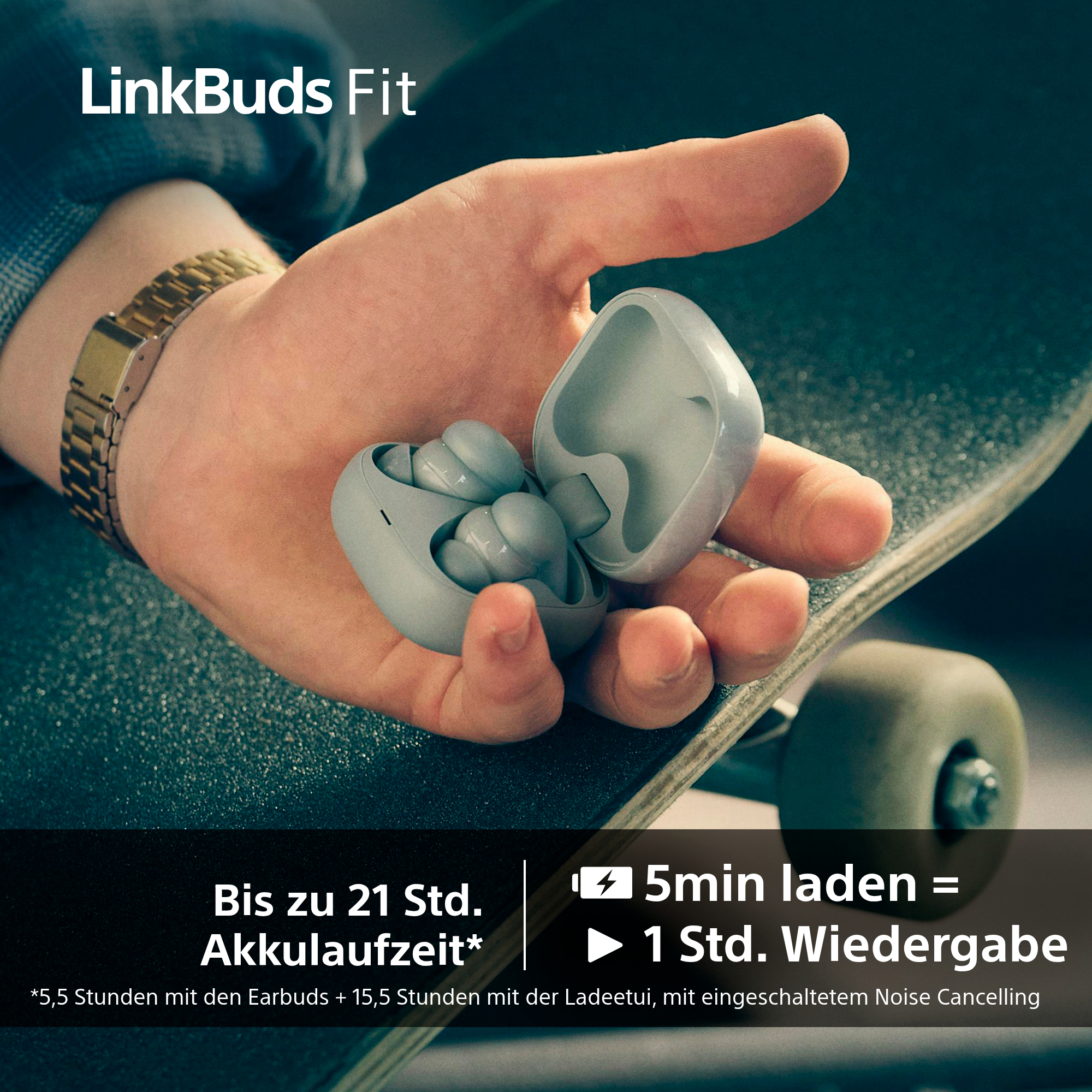 Hand hält offene Ohrhörer-Hülle mit Ohrhörern auf einem Skateboard. Die Hülle und die Ohrhörer sind hellgrau.