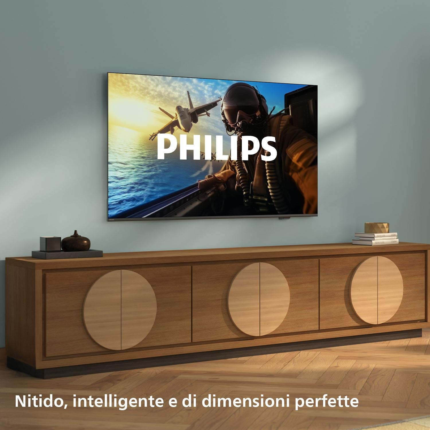 Un televisore mostra un jet da combattimento sull'acqua. La parola PHILIPS è sullo schermo. Sotto, un mobile in legno.