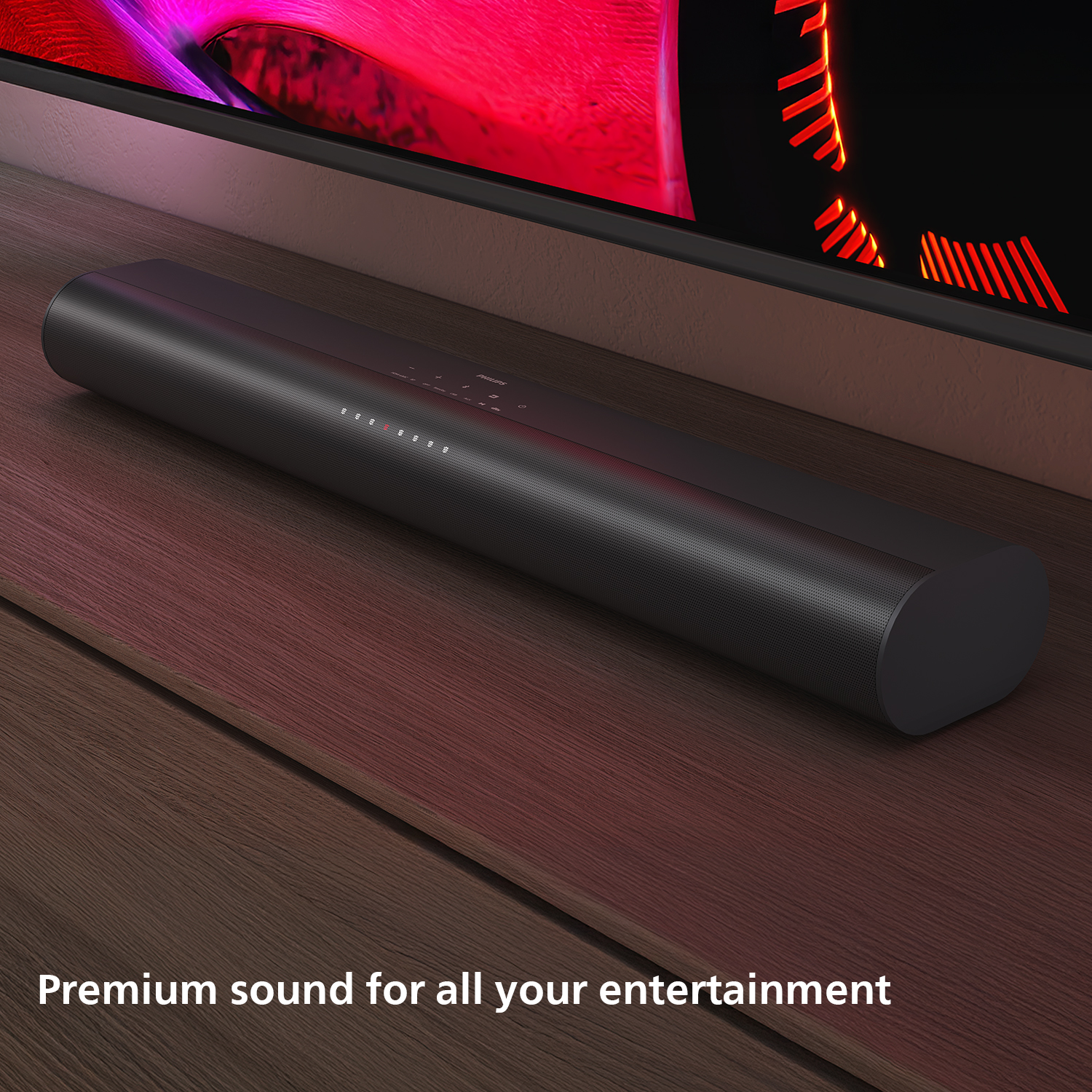 Een zwarte soundbar staat op een houten oppervlak voor een tv. De tv toont rode en oranje patronen.