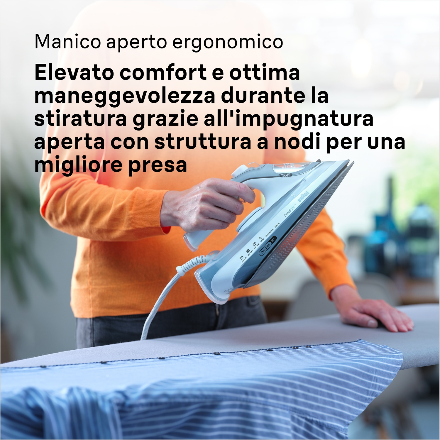 Una persona stira una camicia a righe blu con un ferro da stiro bianco su un asse da stiro grigio. La persona indossa un maglione arancione.