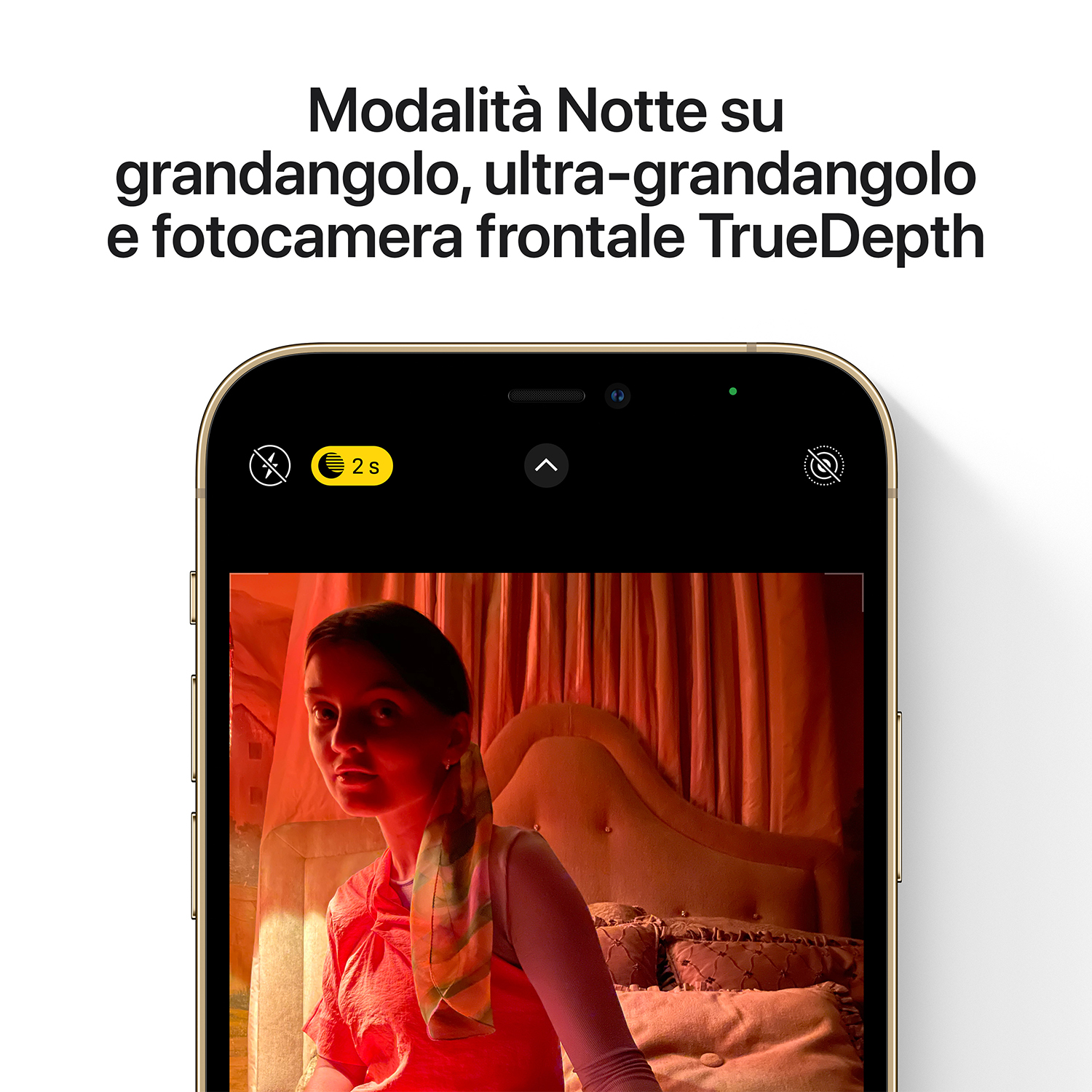 Lo schermo di un telefono mostra una donna in una camera da letto. Lo schermo mostra un'interfaccia della fotocamera con la modalità notturna attivata.