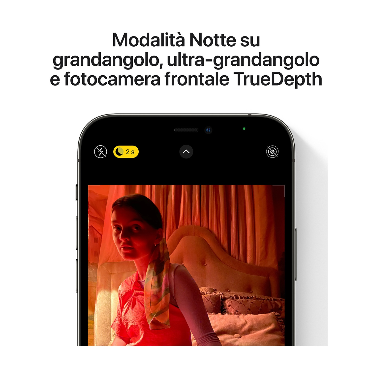 Uno schermo iPhone mostra una donna in una stanza rossa. Lo schermo mostra la modalità Notte. Il testo dice 'Modalità Notte su grandangolo, ultra-grandangolo e TrueDepth'.