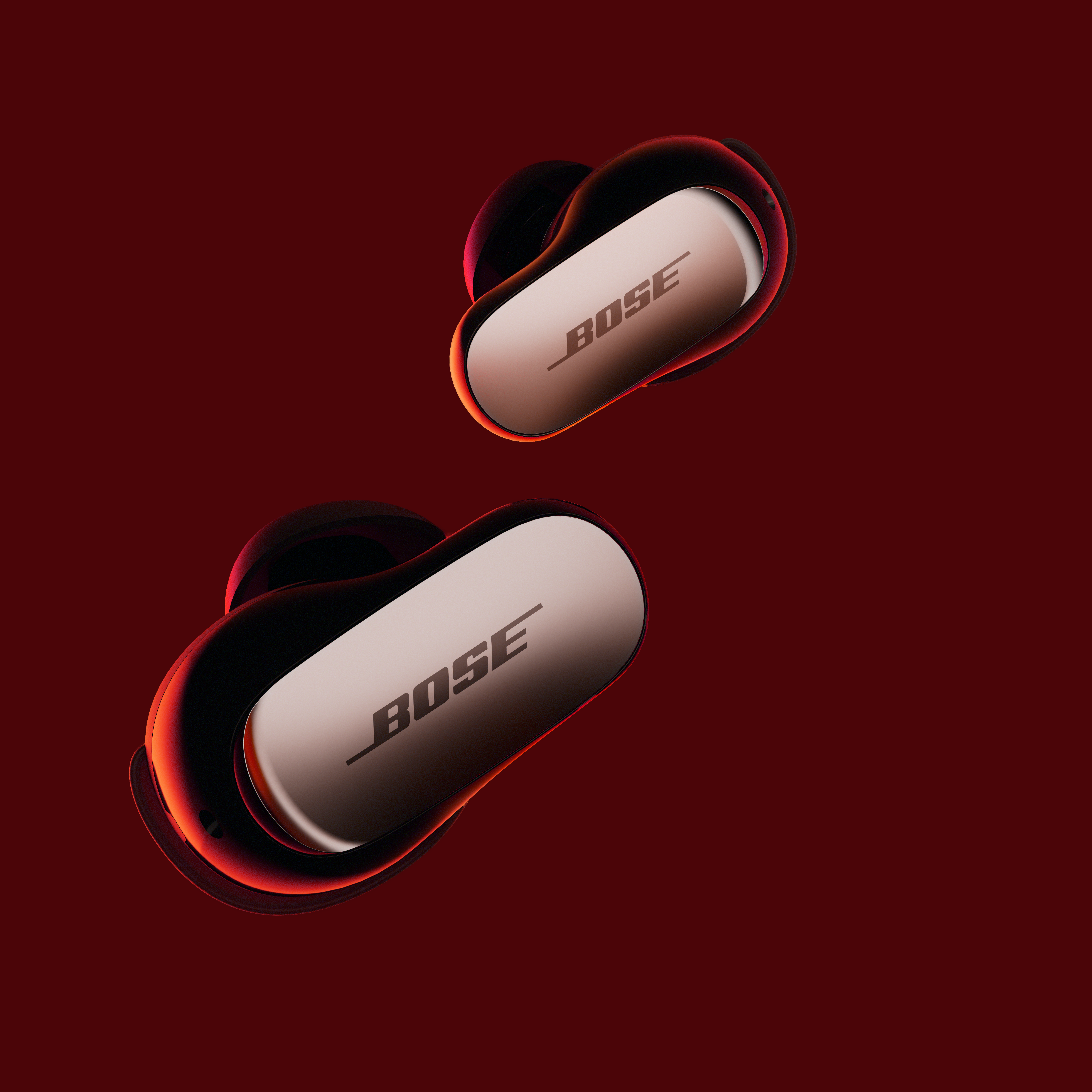 Zwei schwarze und roségoldene Bose-Ohrhörer auf rotem Hintergrund. Das Bose-Logo ist sichtbar.