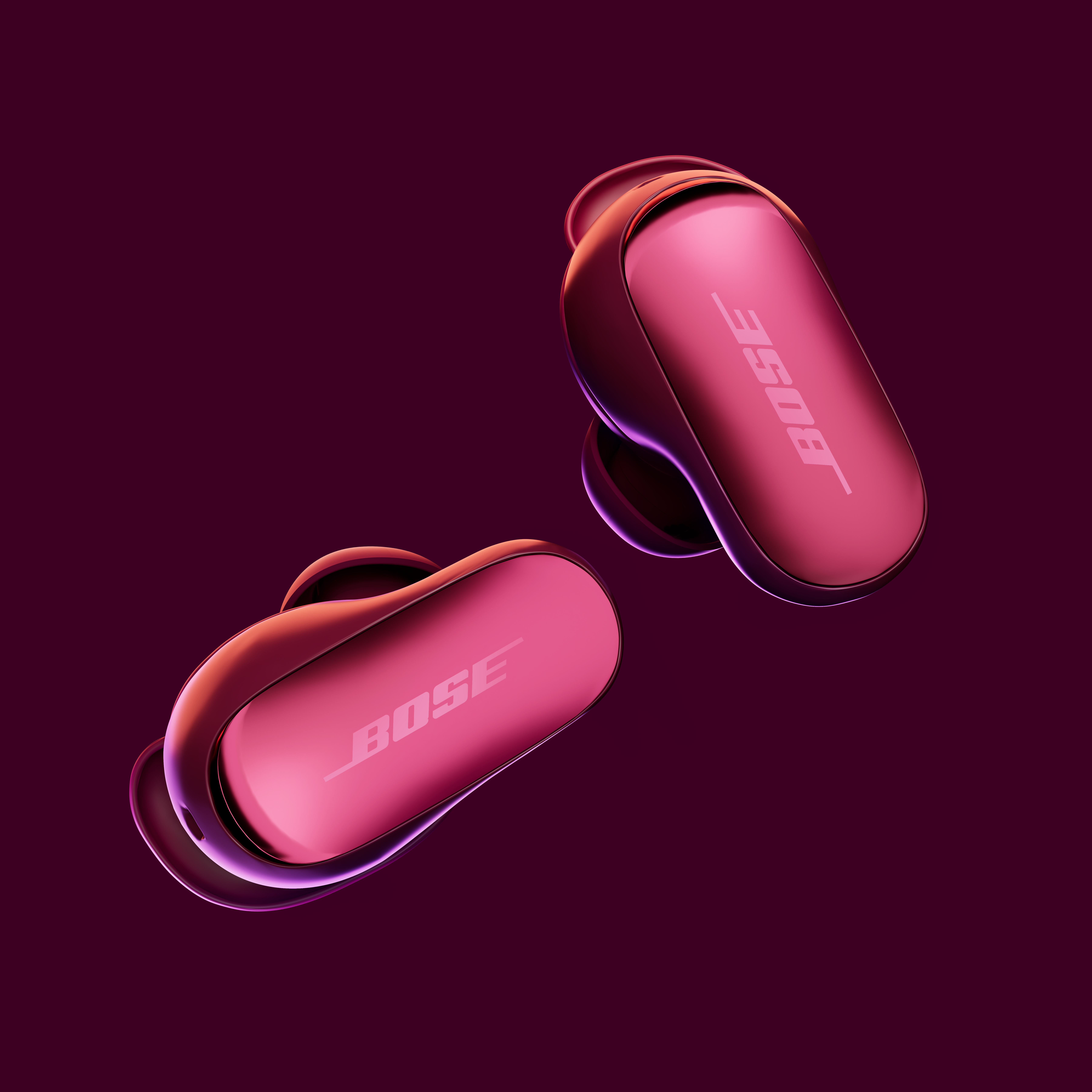 Deux écouteurs Bose roses sur fond violet foncé. Le logo Bose est visible sur les écouteurs.