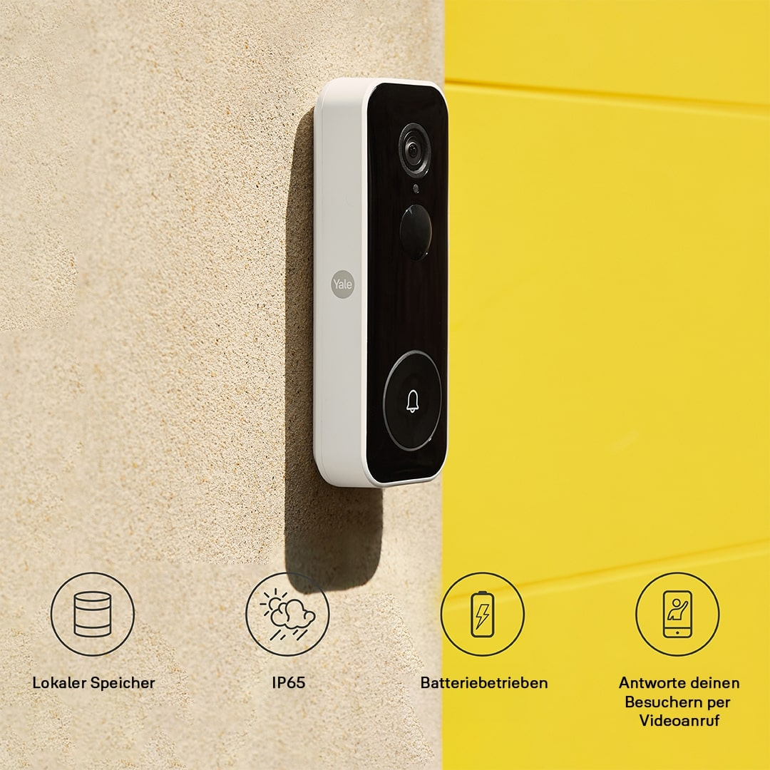 Weiße und schwarze Yale-Türklingel an beiger Wand, gelber Hintergrund. Zeigt Funktionen wie lokaler Speicher und Batteriestrom.