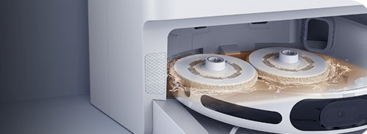 Zbliżenie wnętrza robota czyszczącego z dwiema okrągłymi nakładkami czyszczącymi zanurzonymi w płynie.