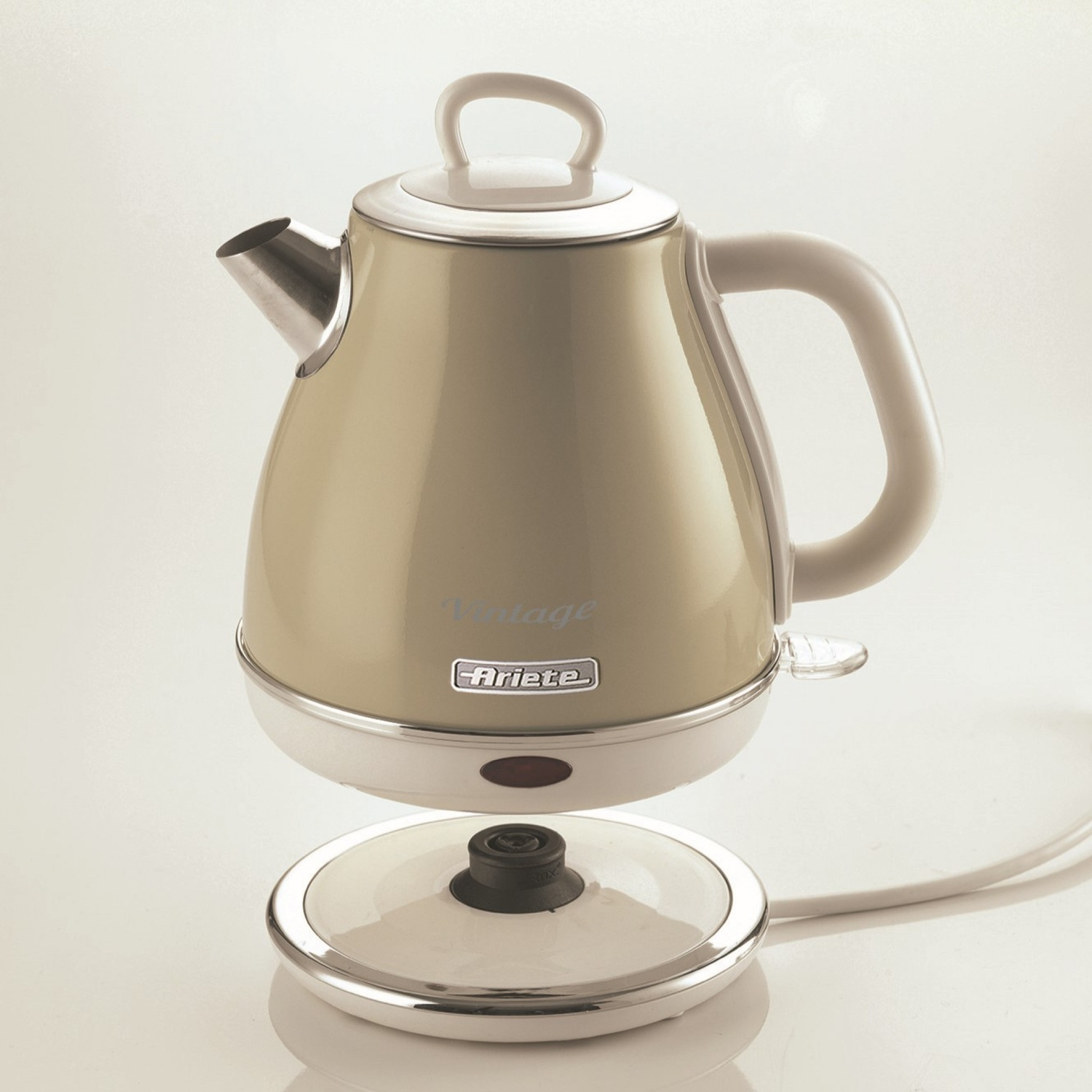 Un bollitore elettrico vintage beige, sulla sua base. Il bollitore ha un manico, un beccuccio e un coperchio. La base ha un cavo.