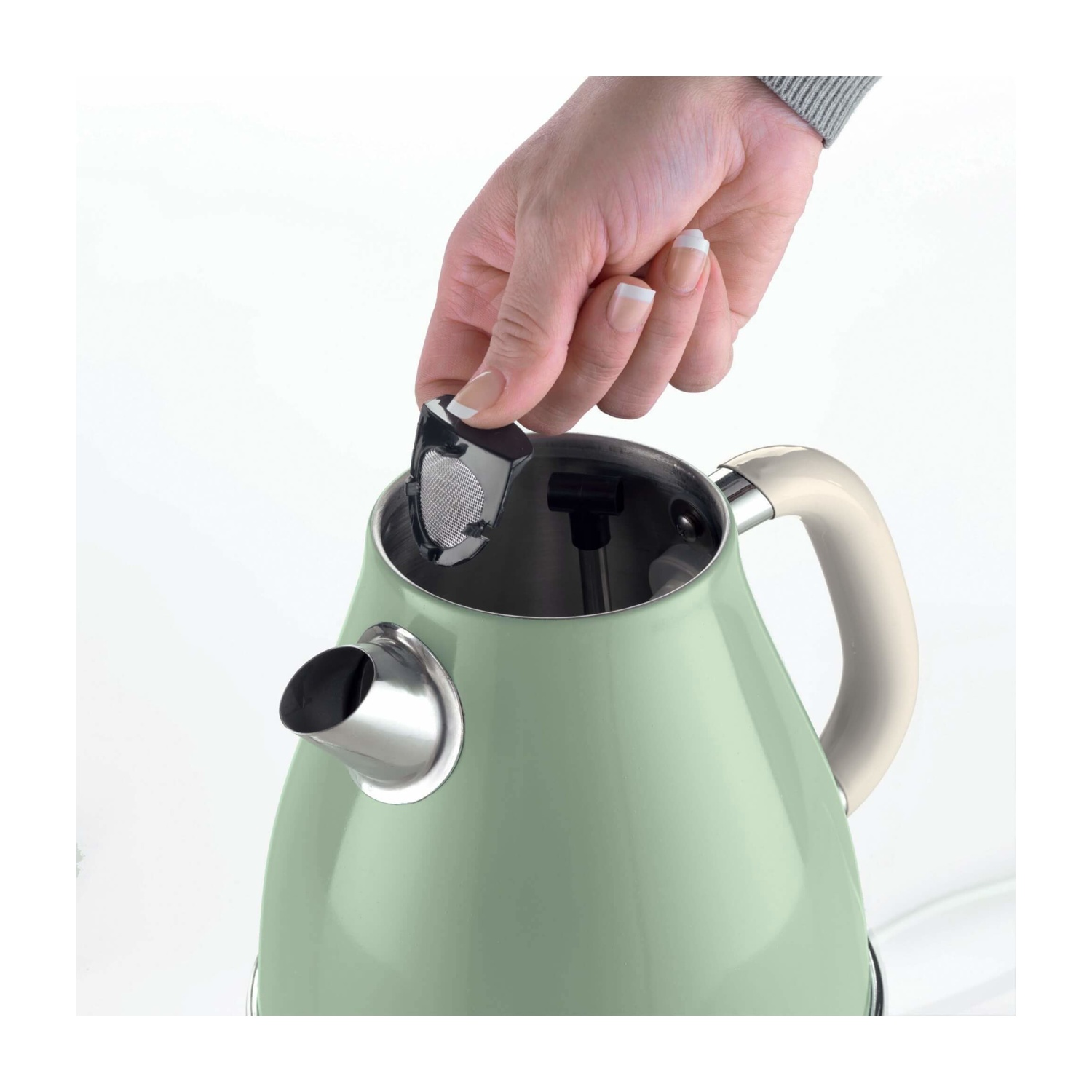 Una mano sta inserendo un filtro in un bollitore verde chiaro. Il bollitore ha un manico bianco. Lo sfondo è bianco.