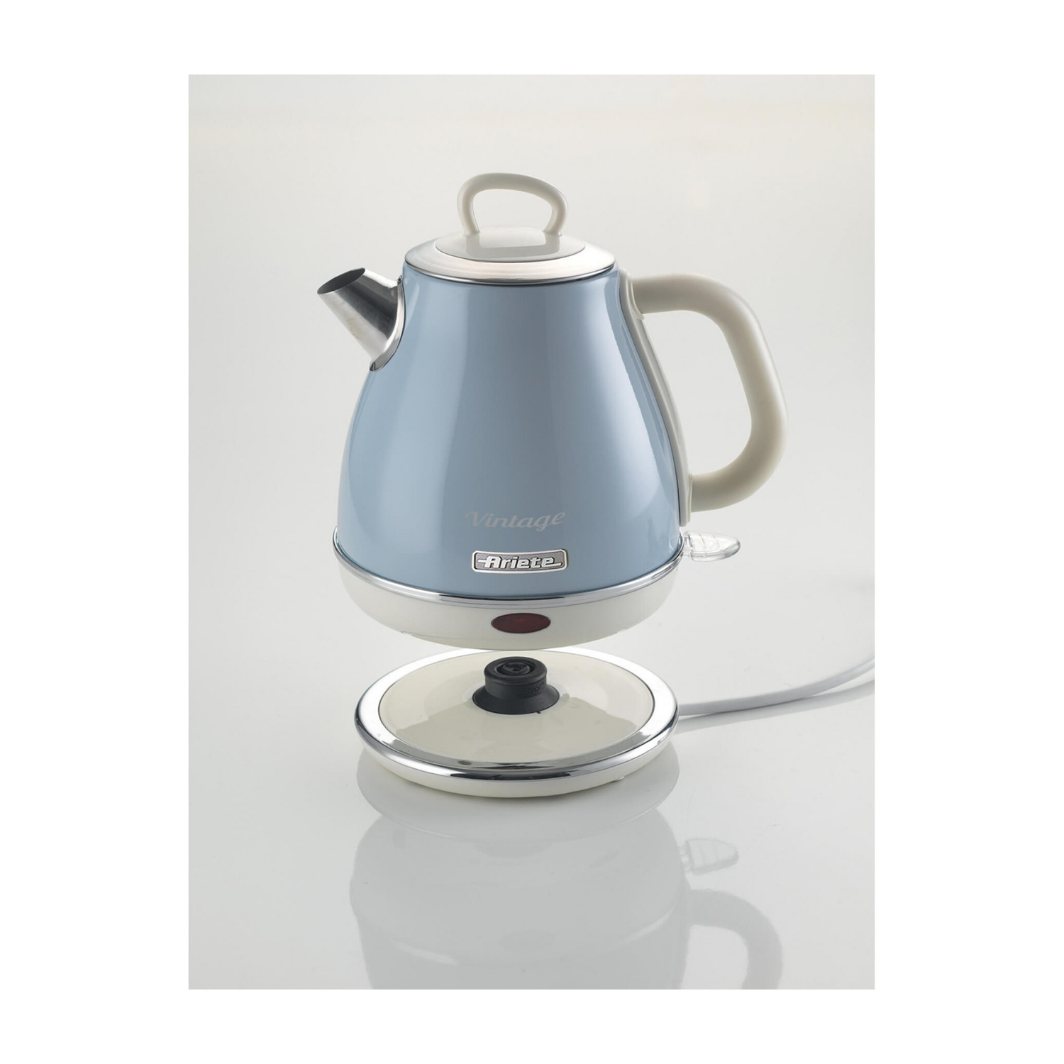 Un bollitore elettrico vintage azzurro con base e manico bianchi. Il bollitore è su una superficie bianca.
