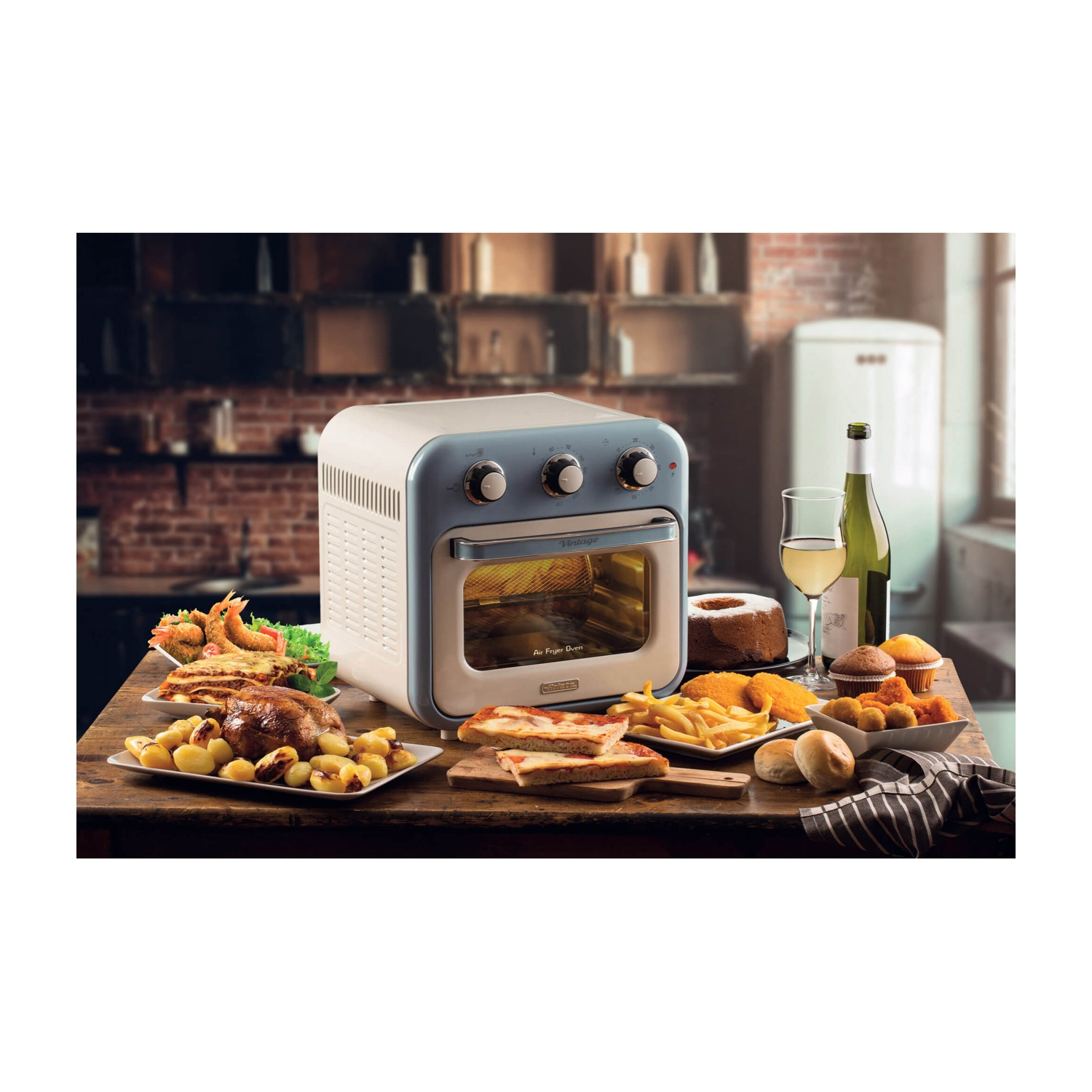 Una friggitrice ad aria con cibo su un tavolo di legno. Include pollo arrosto, pizza, patatine fritte, vino e prodotti da forno.