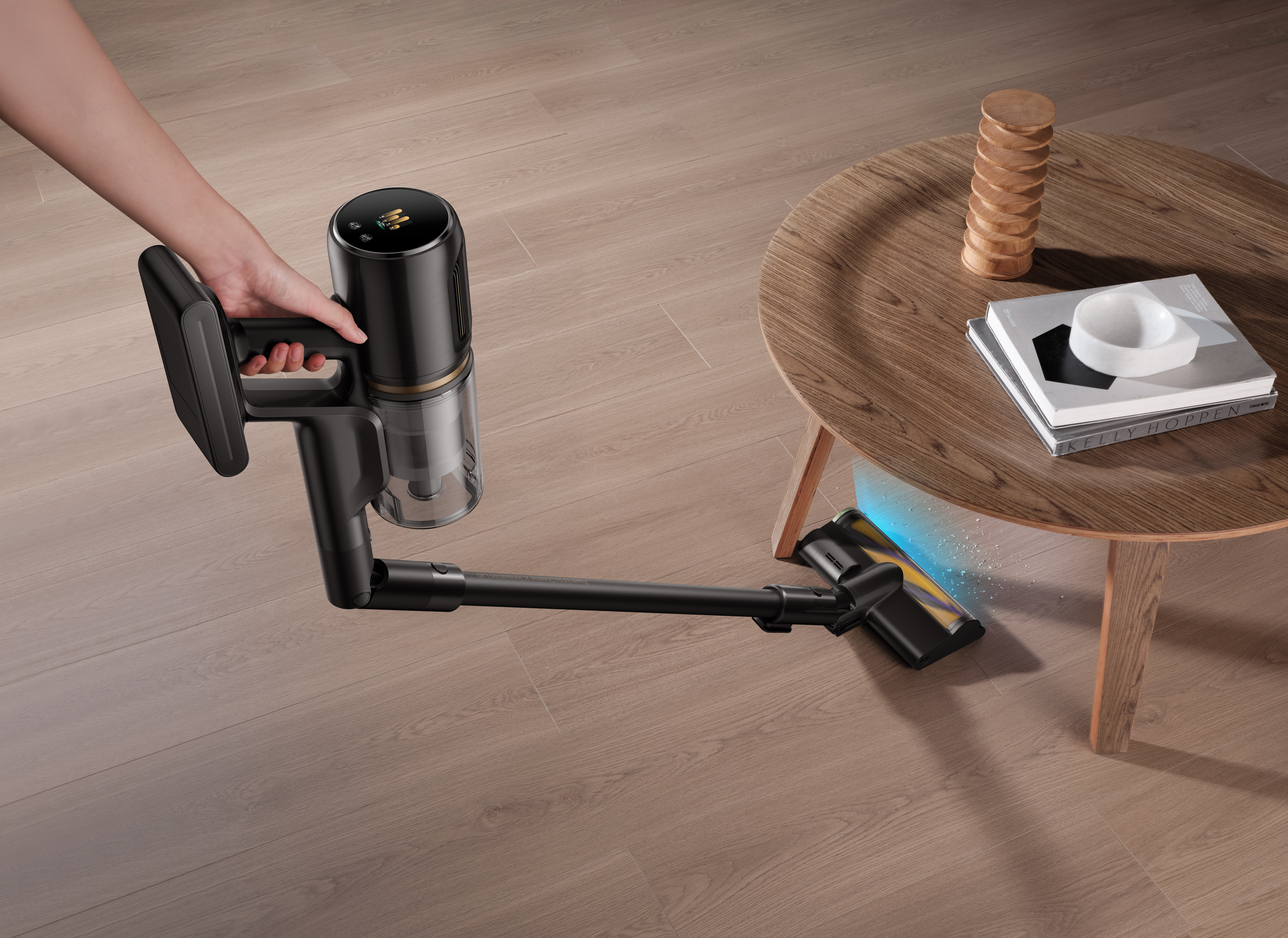 Czarno-złoty odkurzacz jest używany na drewnianej podłodze. W pobliżu znajduje się mały drewniany stolik z książkami.