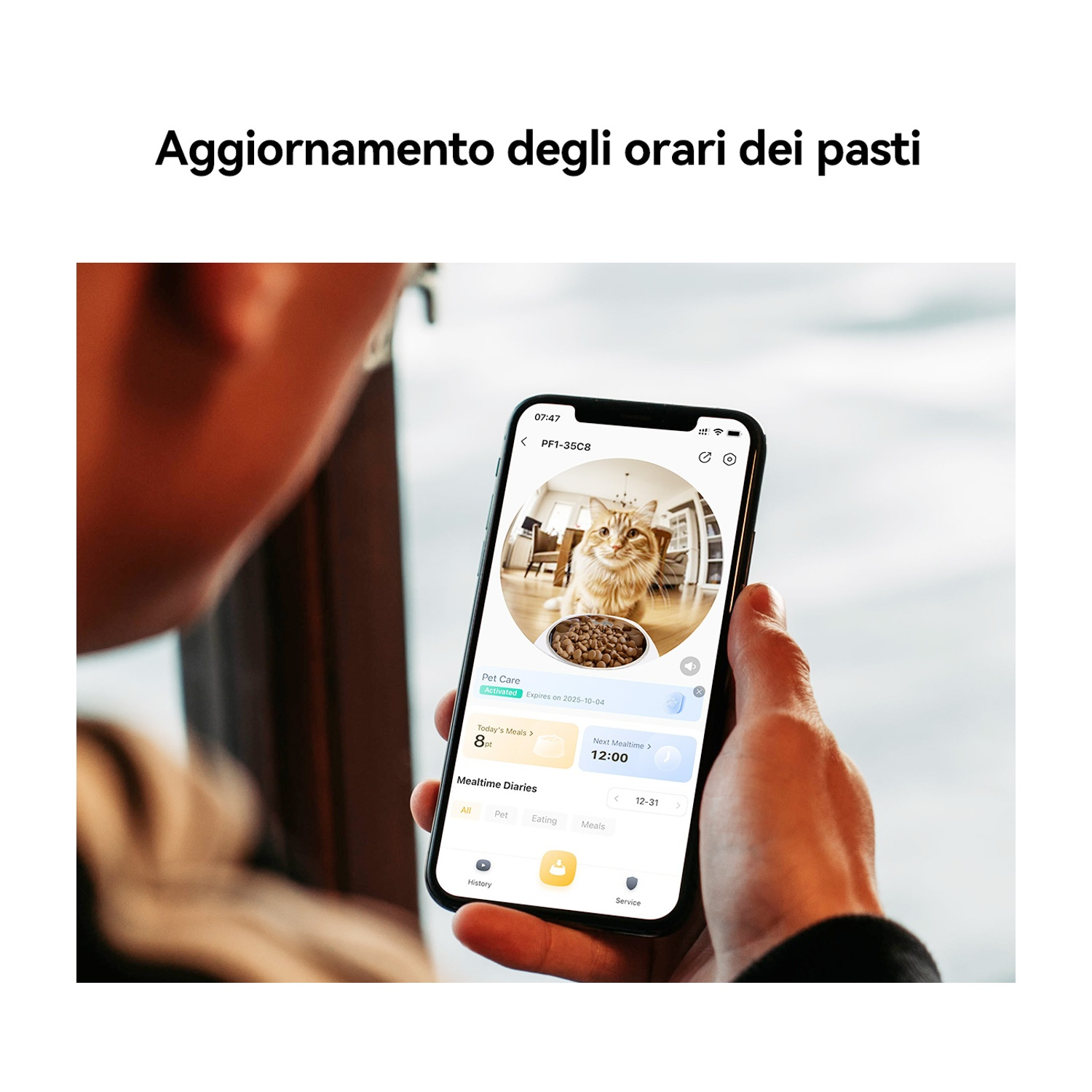 Una persona tiene in mano un telefono che mostra un'immagine di un gatto e le impostazioni dell'ora dei pasti. Lo schermo mostra un gatto, cibo e opzioni.