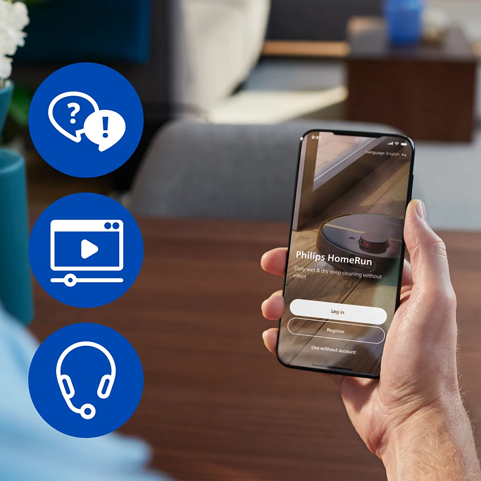 Ręka trzyma telefon z aplikacją Philips HomeRun. Widoczne są ikony i odkurzacz. Tło przedstawia pokój.