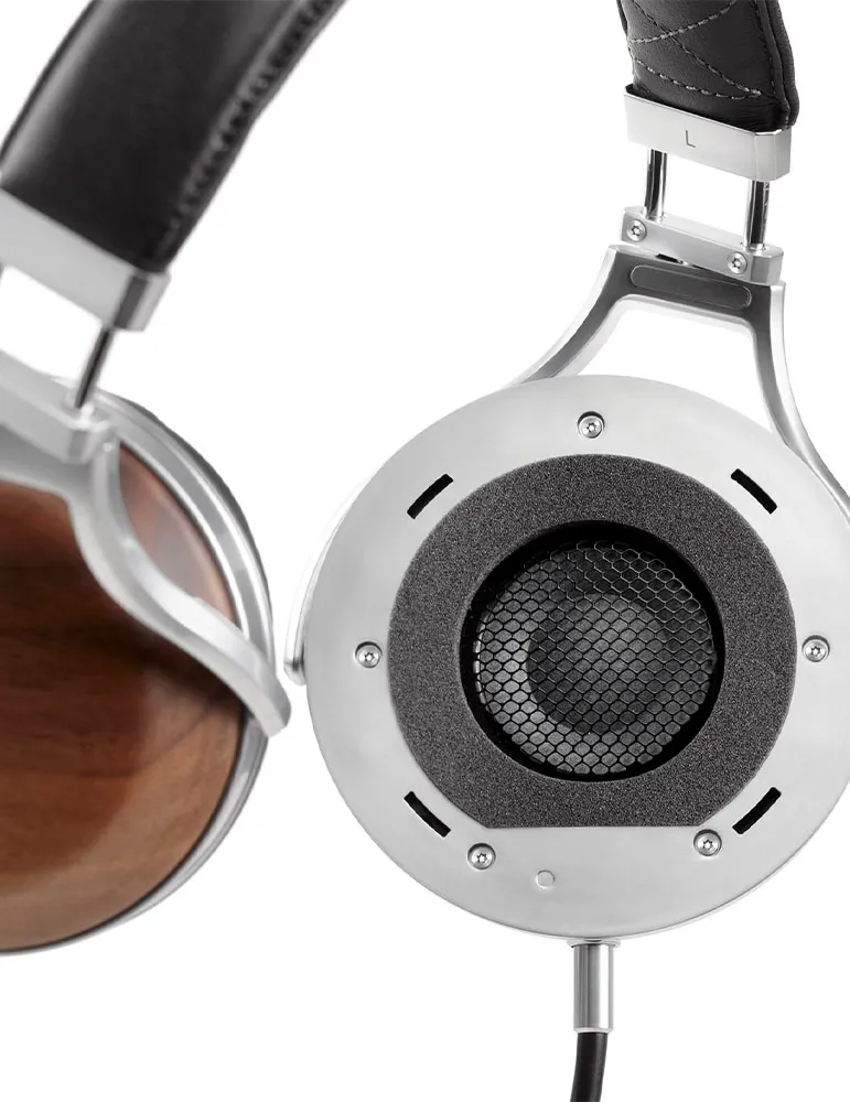 Zbliżenie słuchawek. Srebrna ramka, czarny skórzany pałąk. Drewniana muszla i metalowa siatka. Czarny kabel na dole.