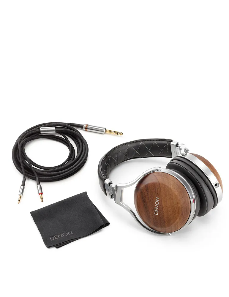 Słuchawki, kabel i ściereczka do czyszczenia na białym tle. Słuchawki mają drewniane nauszniki, srebrne akcenty i czarną skórę. Ściereczka z napisem 'DENON'.
