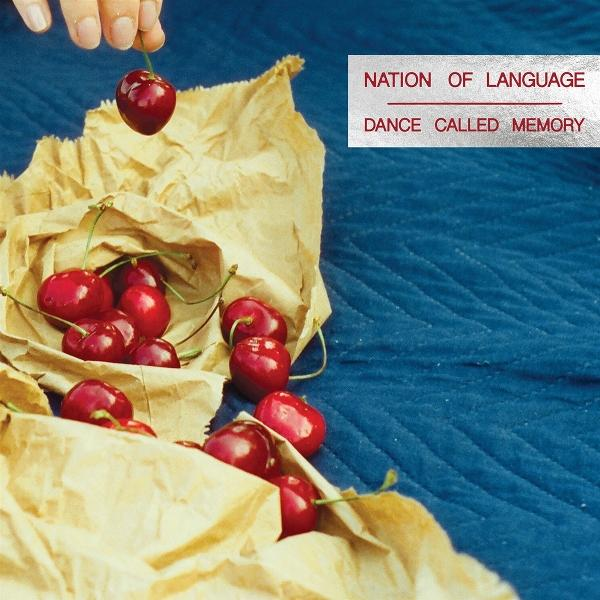 Eine Hand hält eine Kirsche über einem Haufen Kirschen, die aus einer braunen Papiertüte quellen. Der Text lautet: 'Nation of Language, Dance Called Memory'.