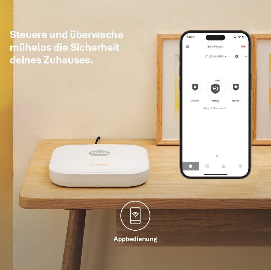Ein weißes Yale-Sicherheitssystem und ein iPhone mit der Yale-App auf einem Holztisch.