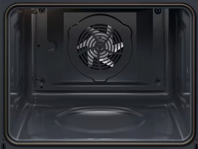 Wnętrze piekarnika. Z tyłu znajduje się wentylator. Ściany piekarnika są ciemnoszare. Dno ma zakrzywioną powierzchnię.