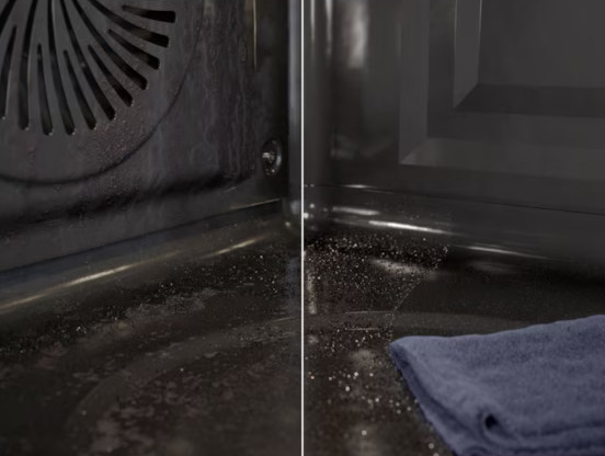 Wnętrze ciemnego piekarnika z wentylatorem po lewej stronie. Widoczne krople wody, po prawej niebieska szmatka.