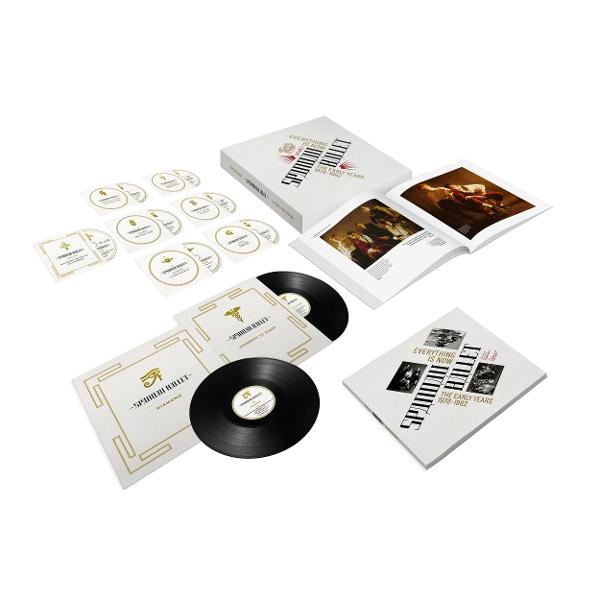 Eine Box mit Schallplatten, Broschüren und CDs. Die Verpackung ist weiß mit goldener Schrift und enthält den Bandnamen und Albumdetails.
