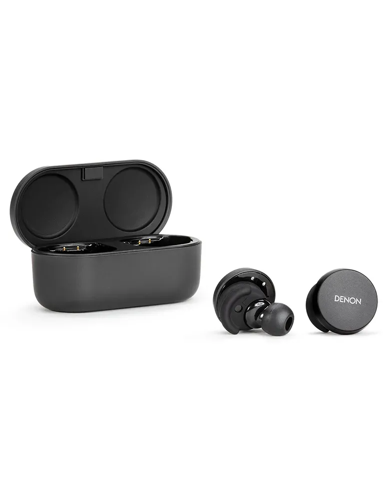 Czarne bezprzewodowe słuchawki z etui ładującym. Jedna słuchawka jest w etui, pozostałe w pobliżu. Marka to Denon.